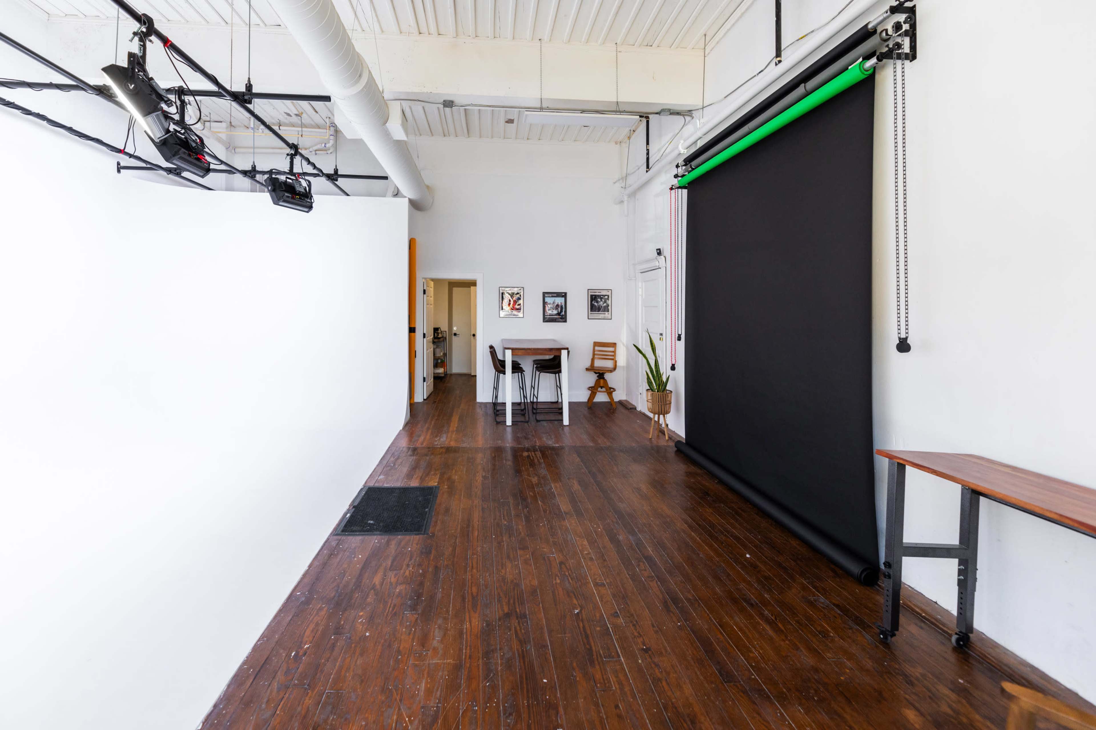 A spacious studio with wooden flooring, white walls, and a black backdrop setup along one side.