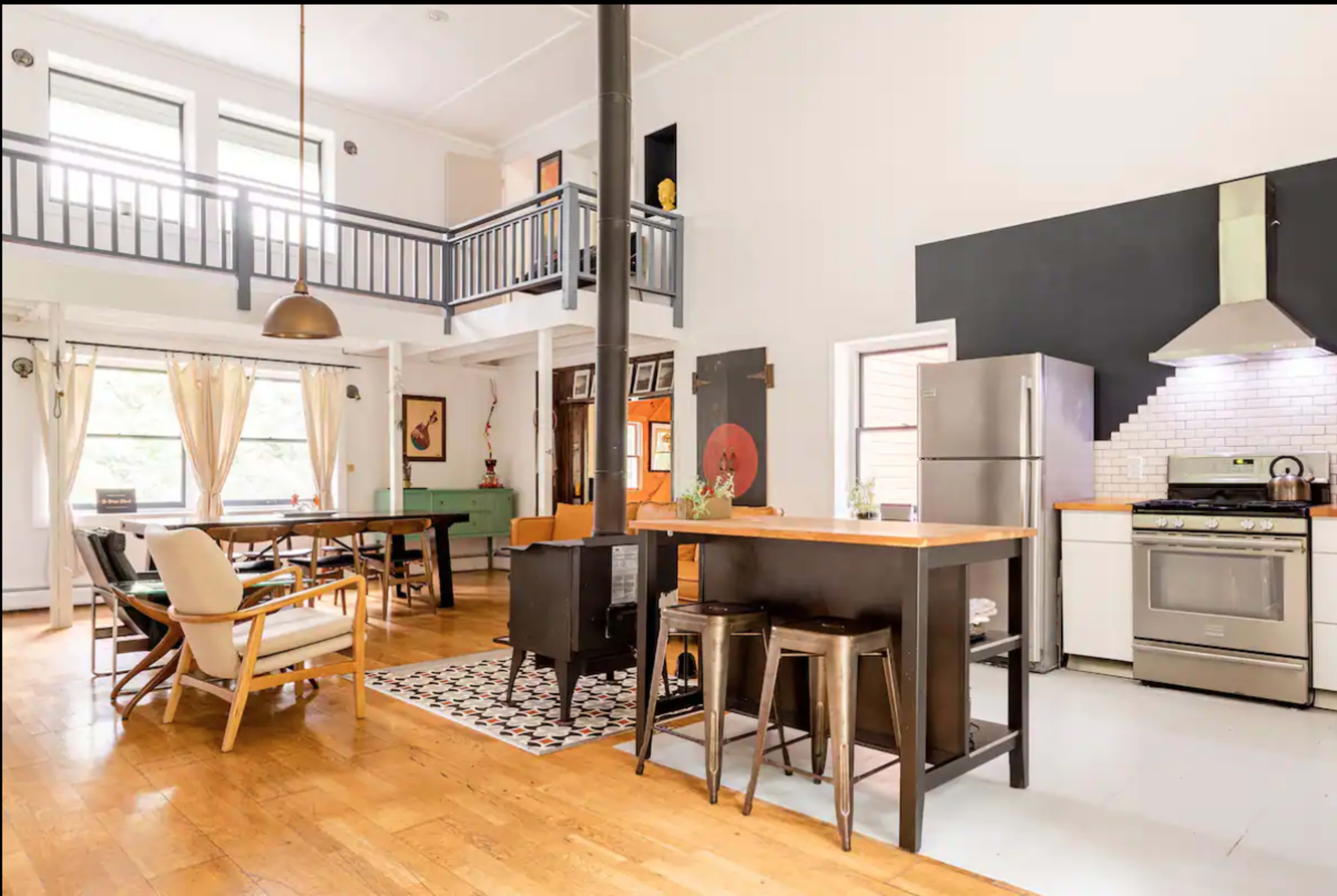 The image shows a modern open-concept kitchen and dining area with wood flooring, featuring a central island and a dining table.
