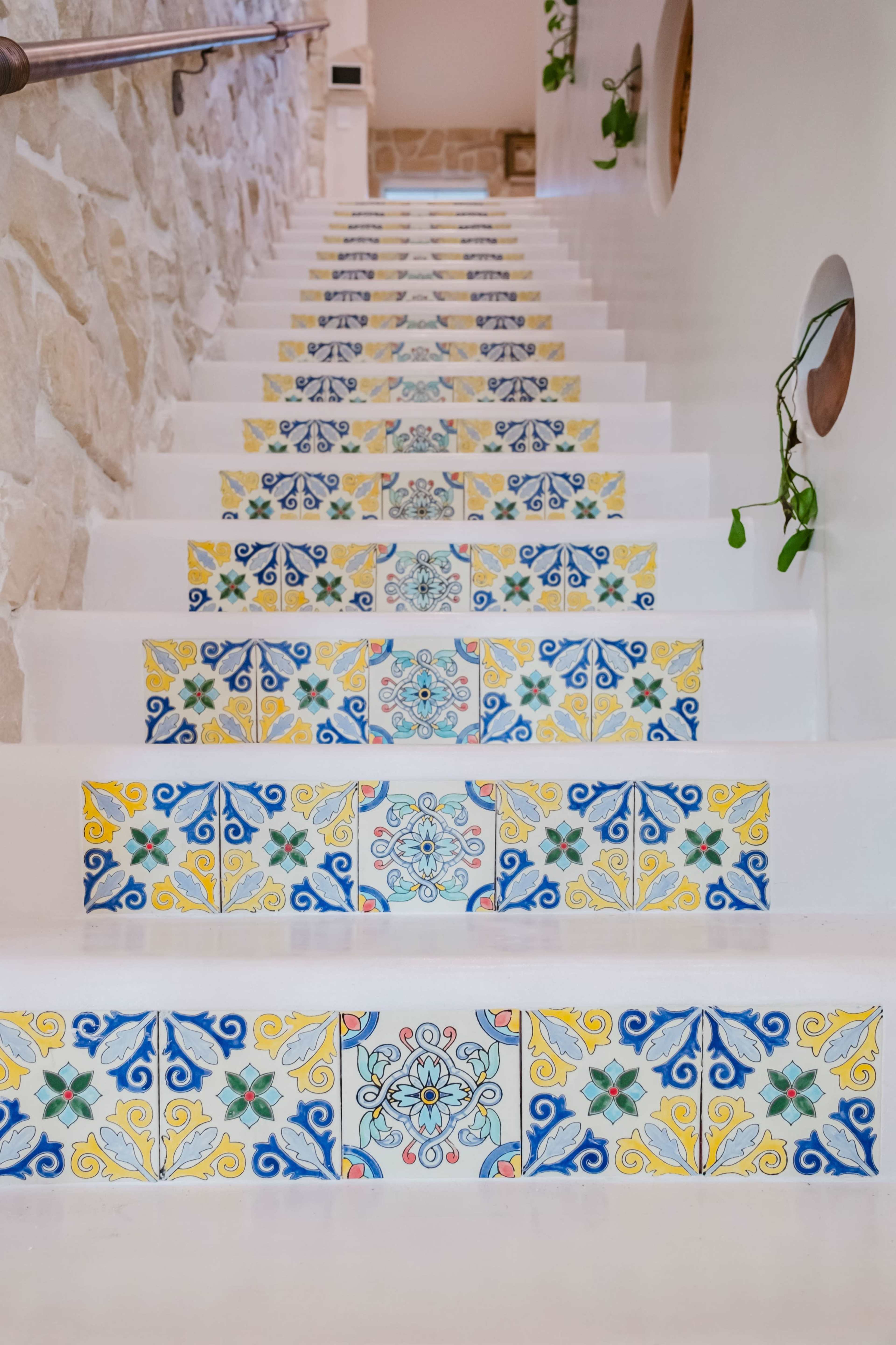 The image depicts a staircase with white steps adorned with colorful decorative tiles featuring intricate patterns.