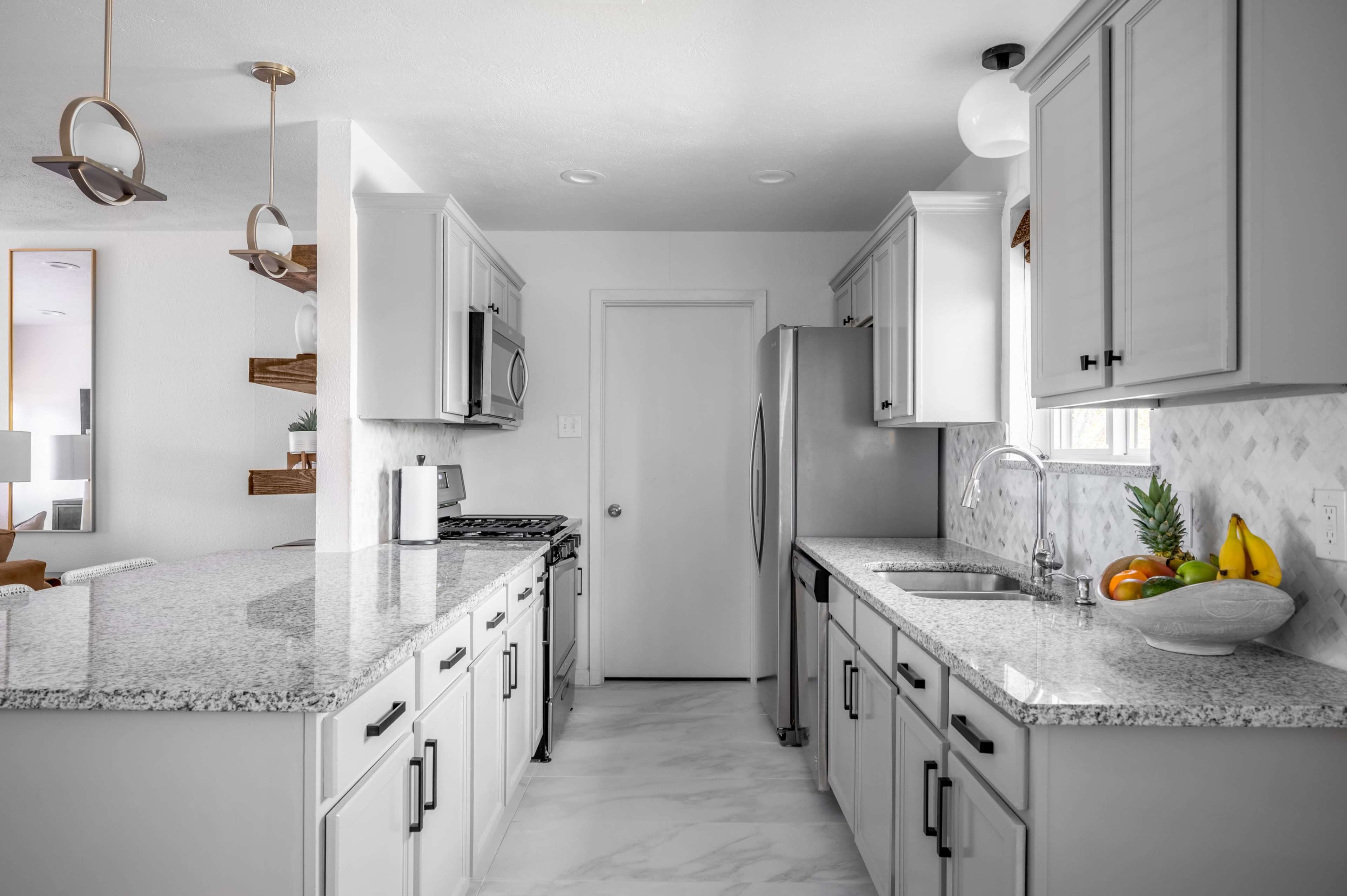 A modern kitchen with gray cabinets, stainless steel appliances, and a granite countertop.