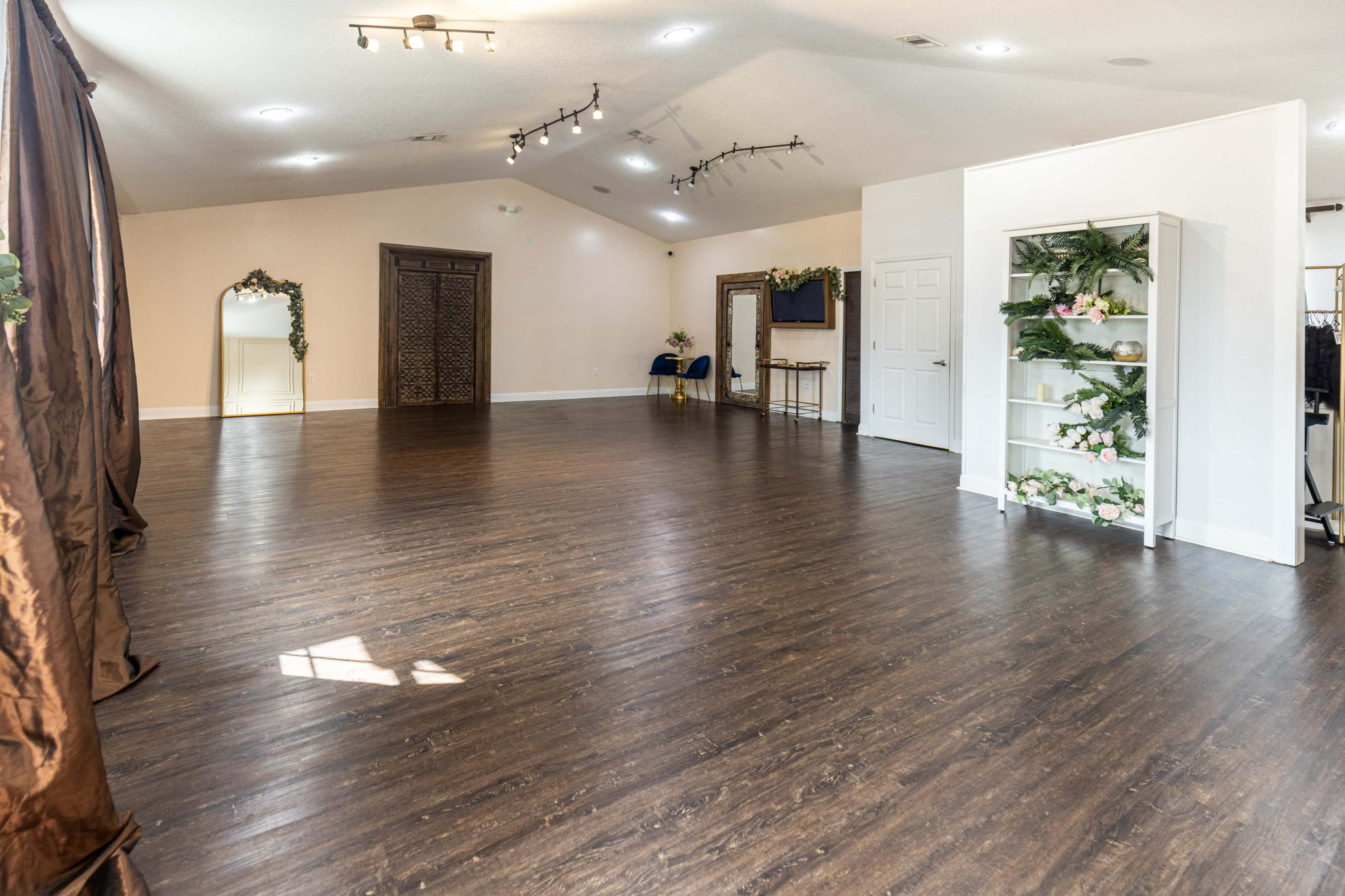An empty indoor space with wooden floors, minimal furniture, and soft lighting.