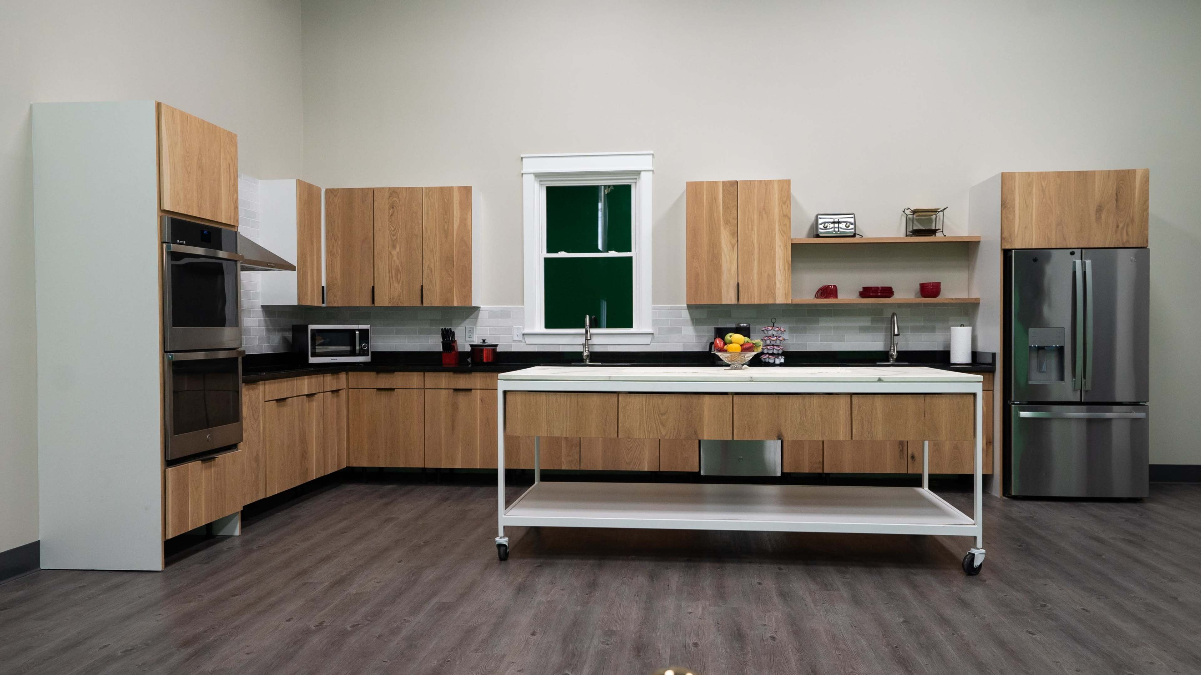 The image shows a modern kitchen featuring wooden cabinetry, stainless steel appliances, and a central island on wheels.