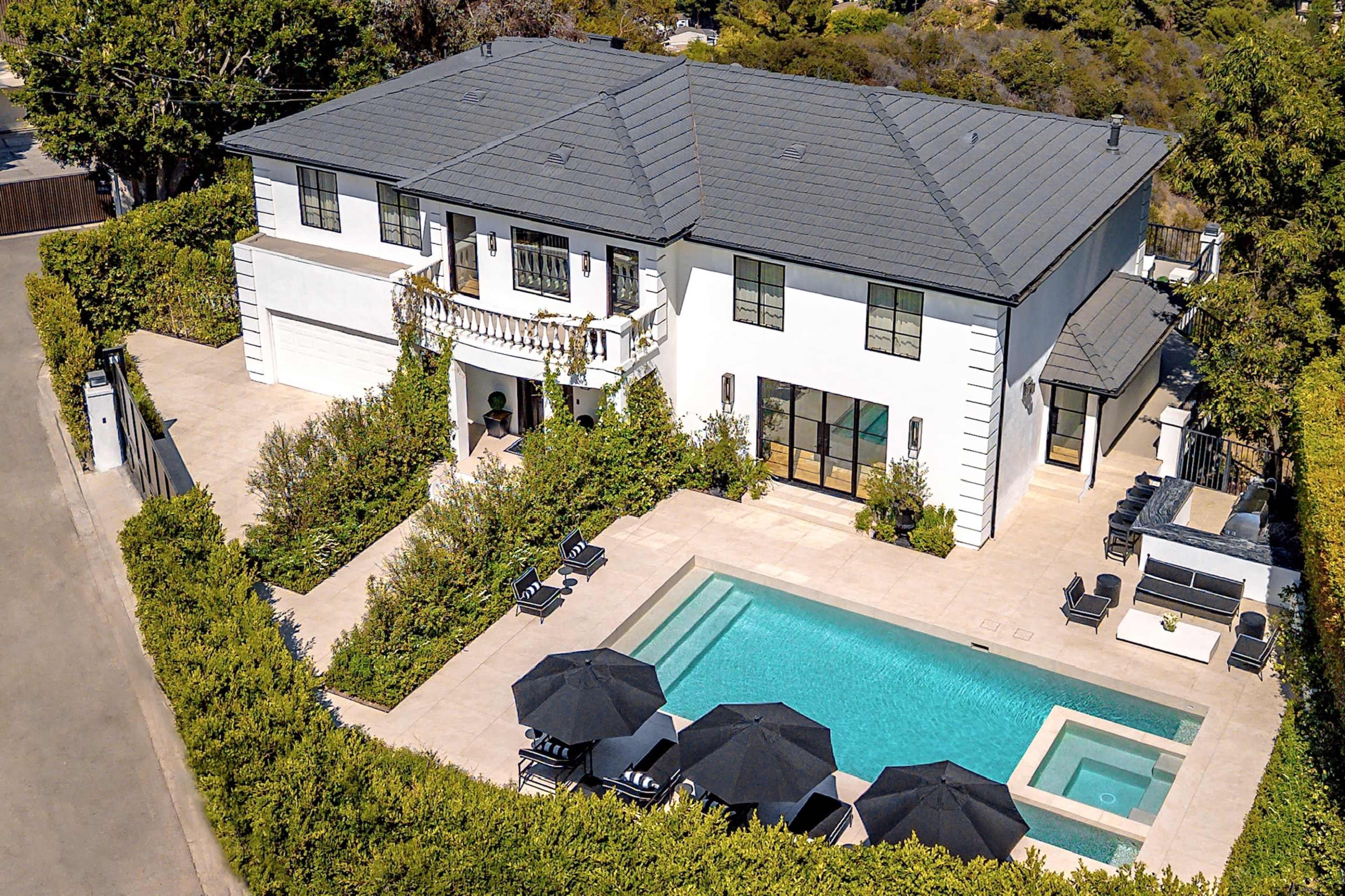The image shows a modern two-story house with a swimming pool and landscaped surroundings.
