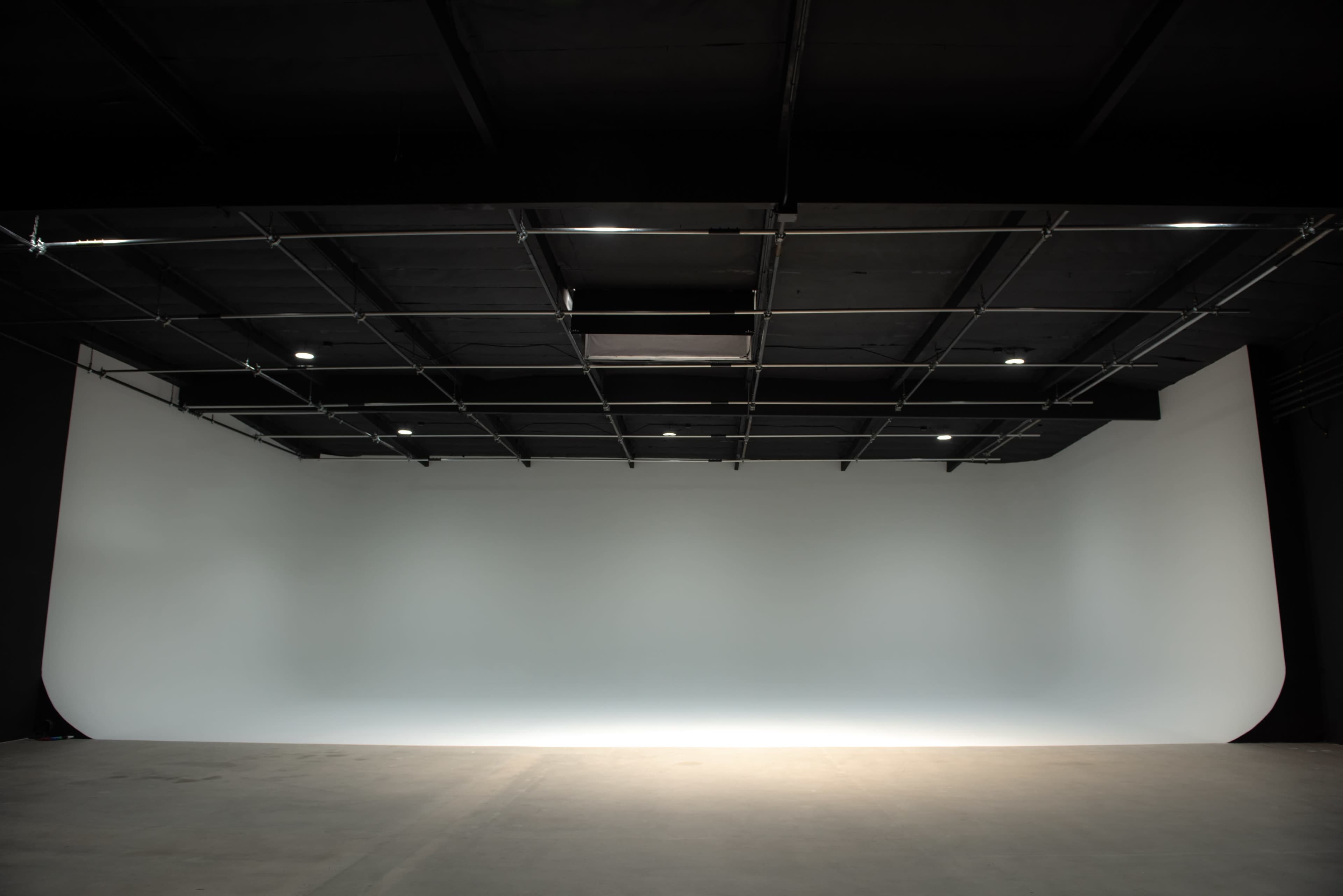 A spacious photography studio with a seamless backdrop and overhead lighting.