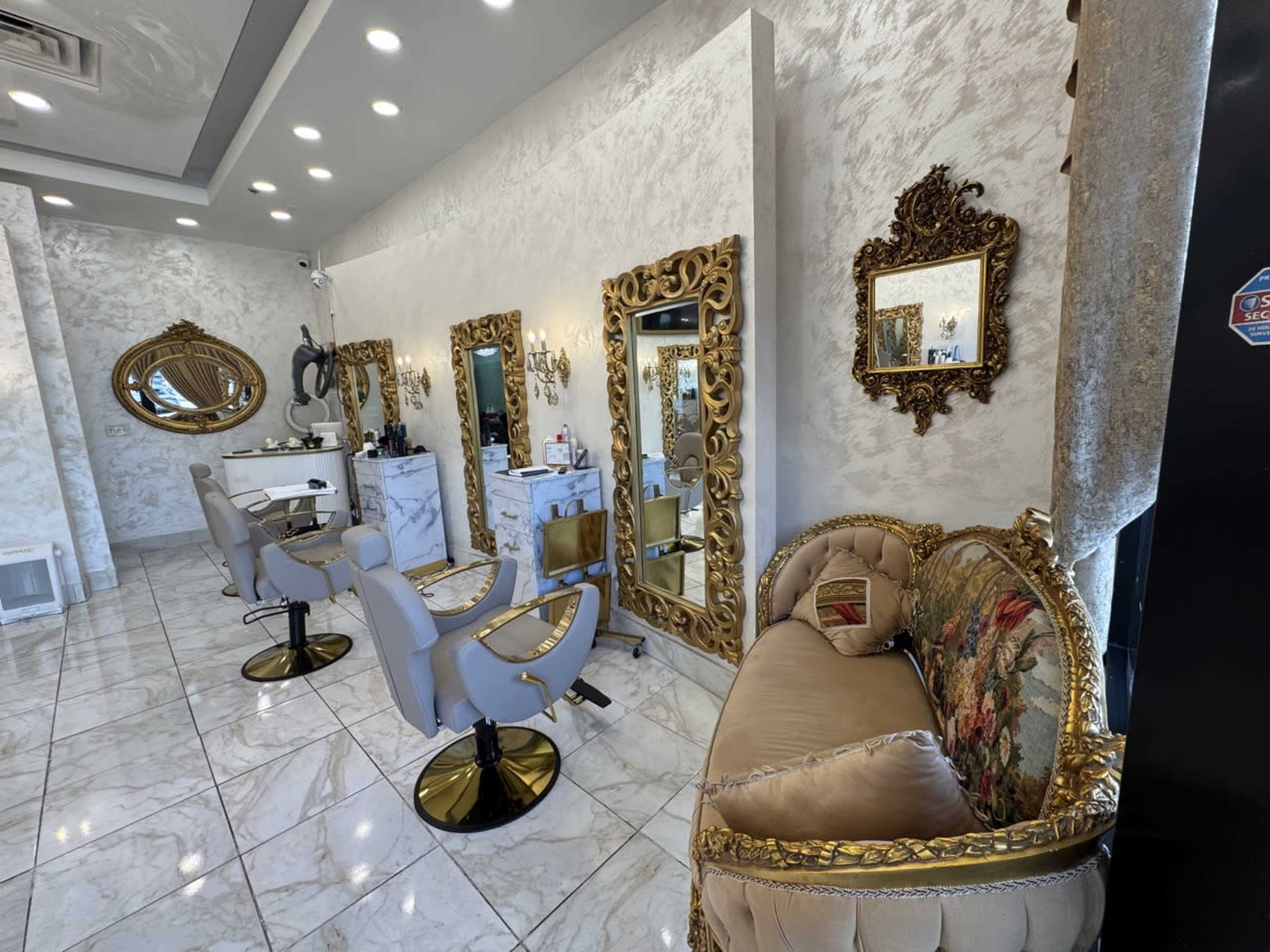 The image shows a stylish salon interior with ornate mirrors, elegant chairs, and marble flooring.