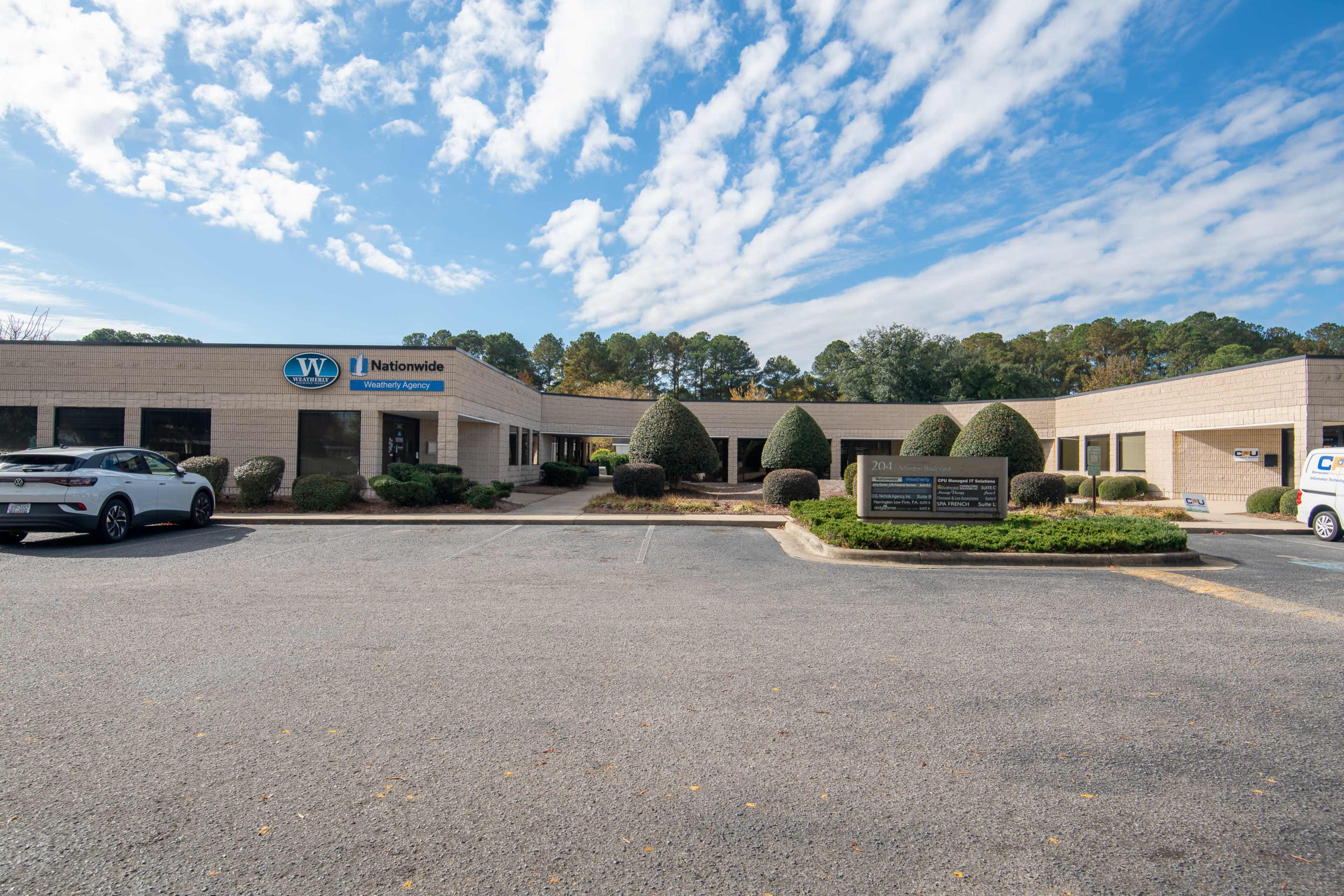A single-story commercial building with a Nationwide logo, surrounded by neatly trimmed bushes and a clear blue sky.