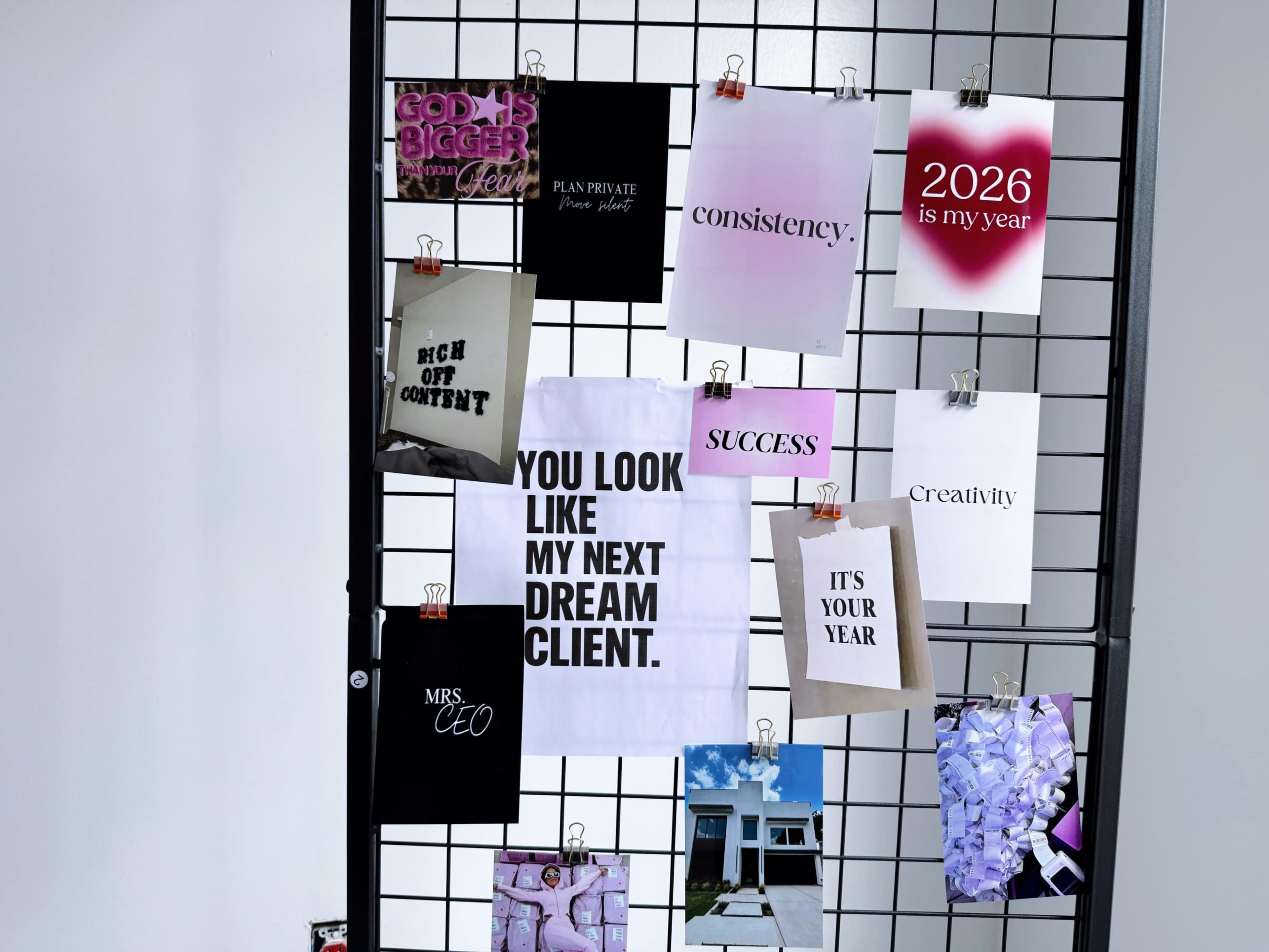 The image shows a wall display grid featuring various motivational posters and notes, including phrases like "2026 is my year" and "YOU LOOK LIKE MY NEXT DREAM CLIENT."