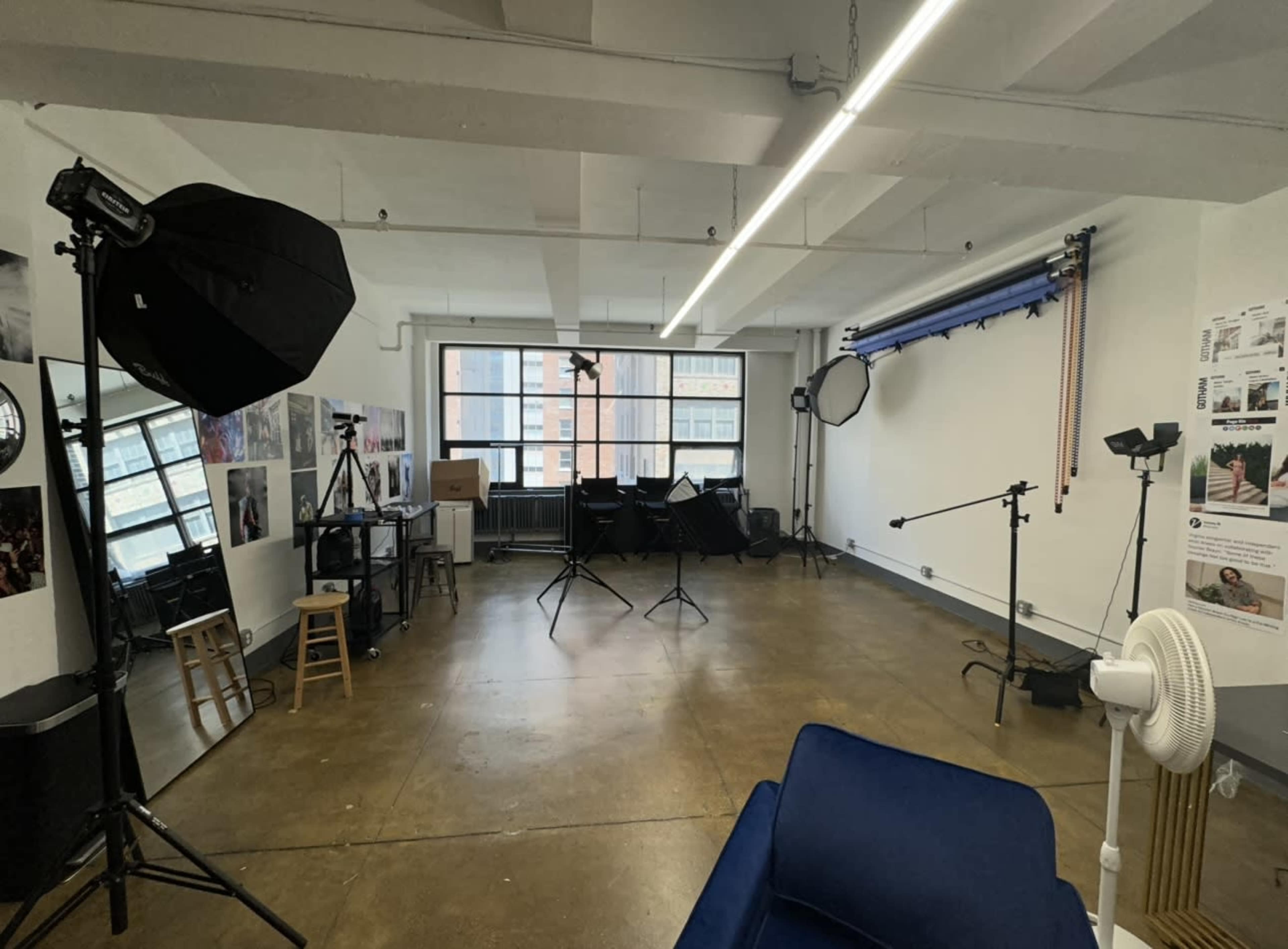 A large, open studio space with various lighting equipment and reflective surfaces set up for photography.