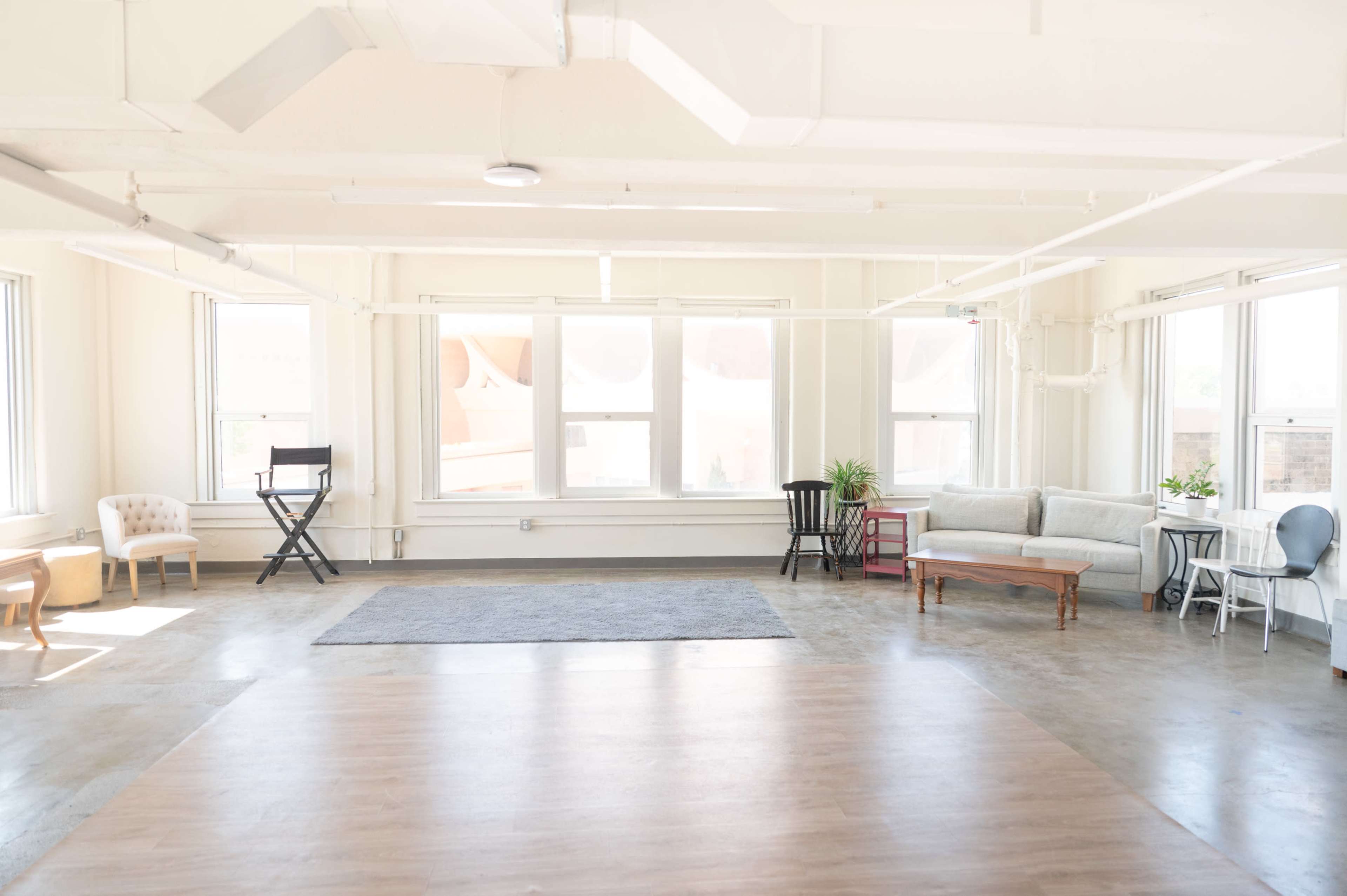 The image shows a spacious, well-lit room with a mix of seating options arranged around a central area.