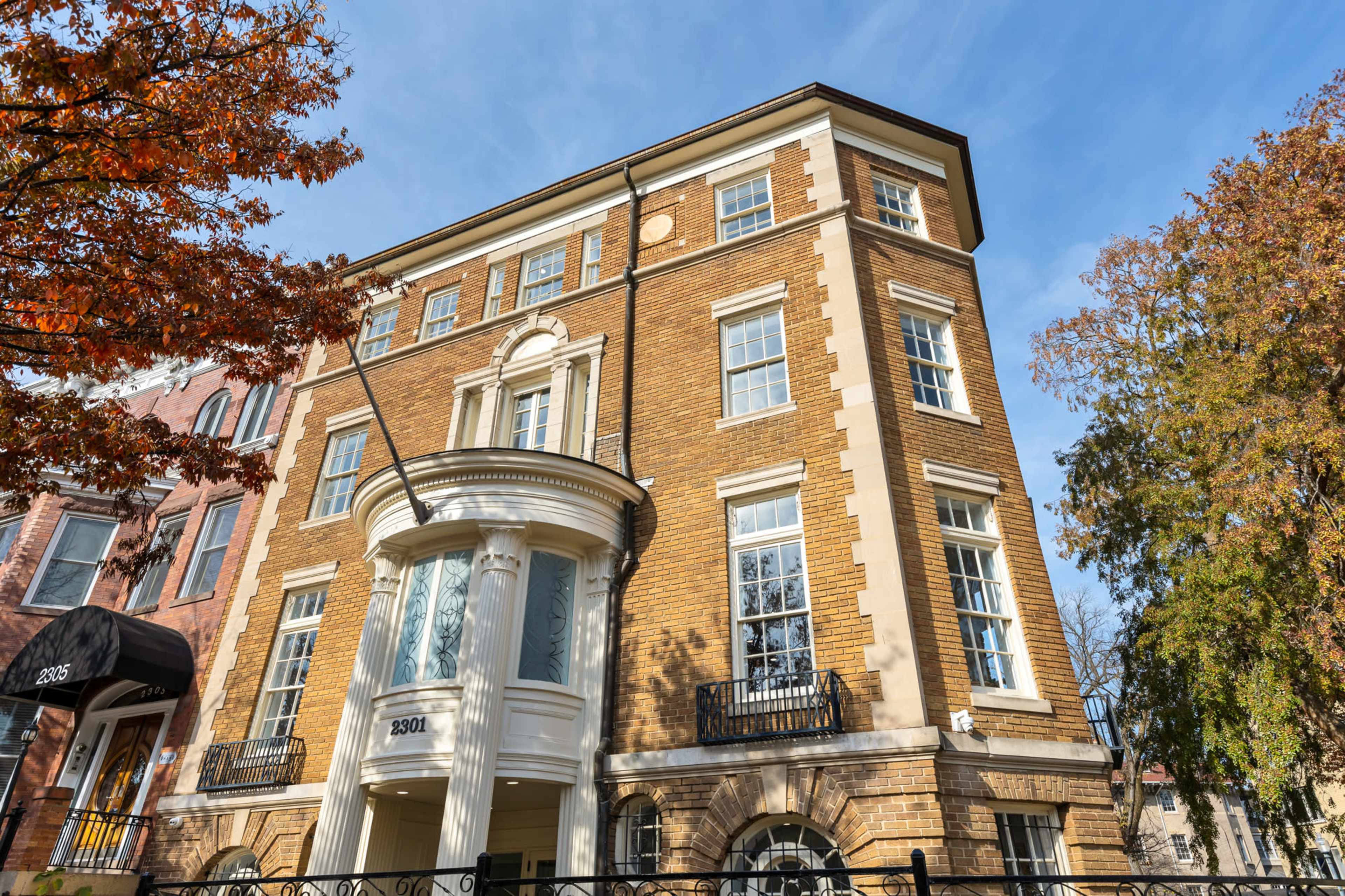 A four-story brick building with a prominent entryway featuring large windows and a curved porch.