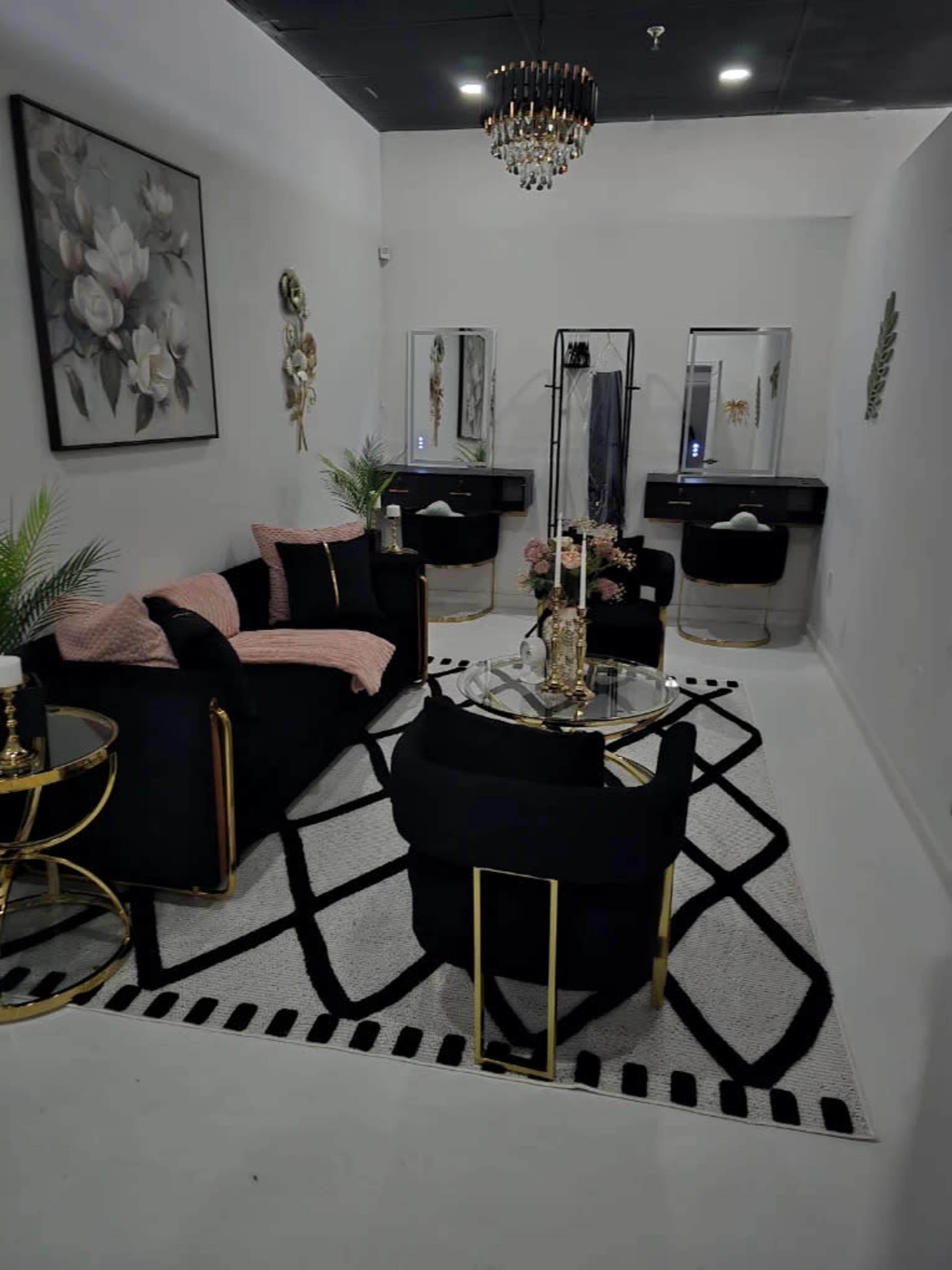 The image shows a modern, well-decorated interior space featuring a black and gold color scheme with a seating area, a stylish coffee table, and decorative elements on the walls.