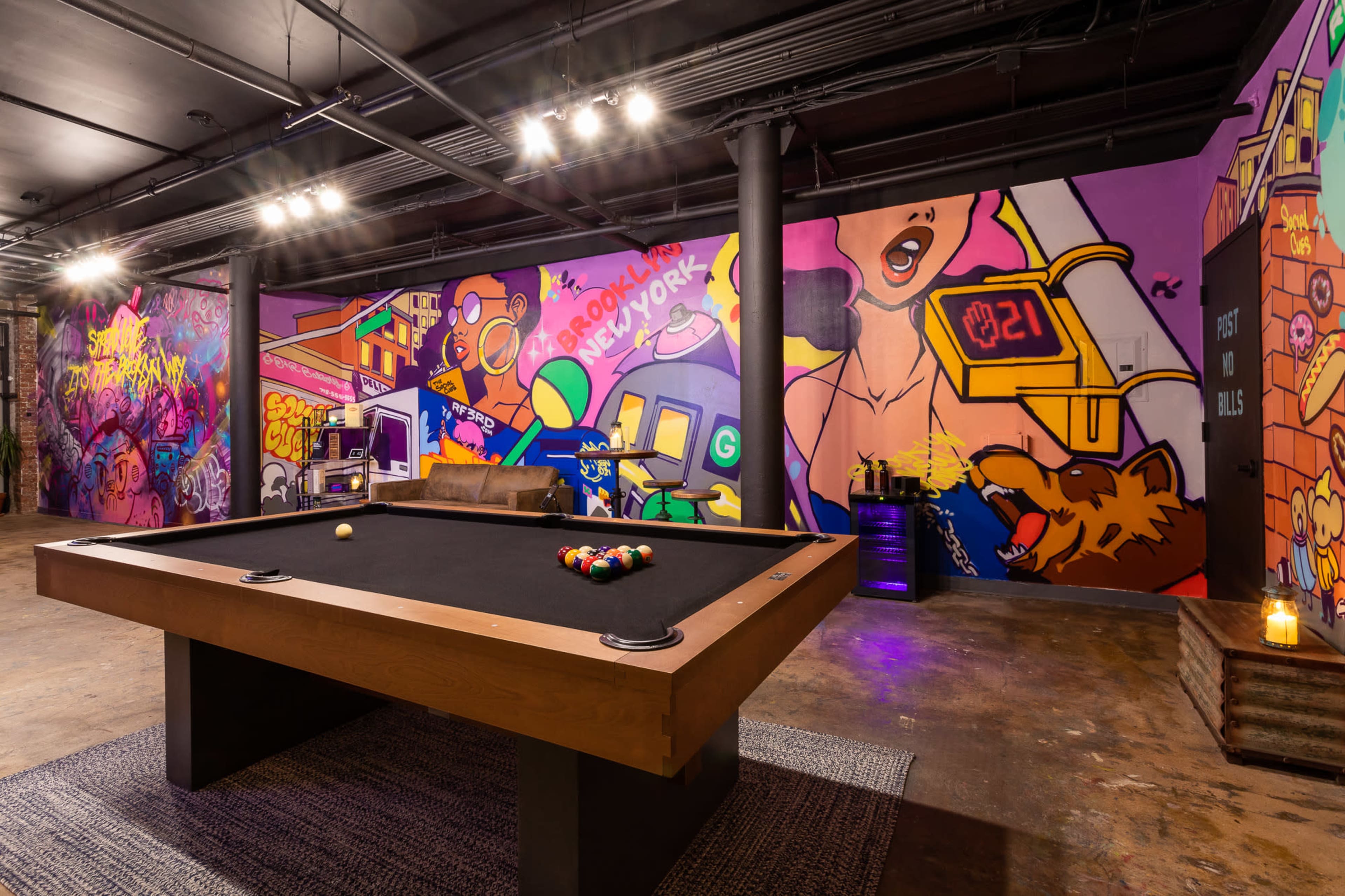 A billiard table in a vibrant room adorned with colorful graffiti murals on the walls.
