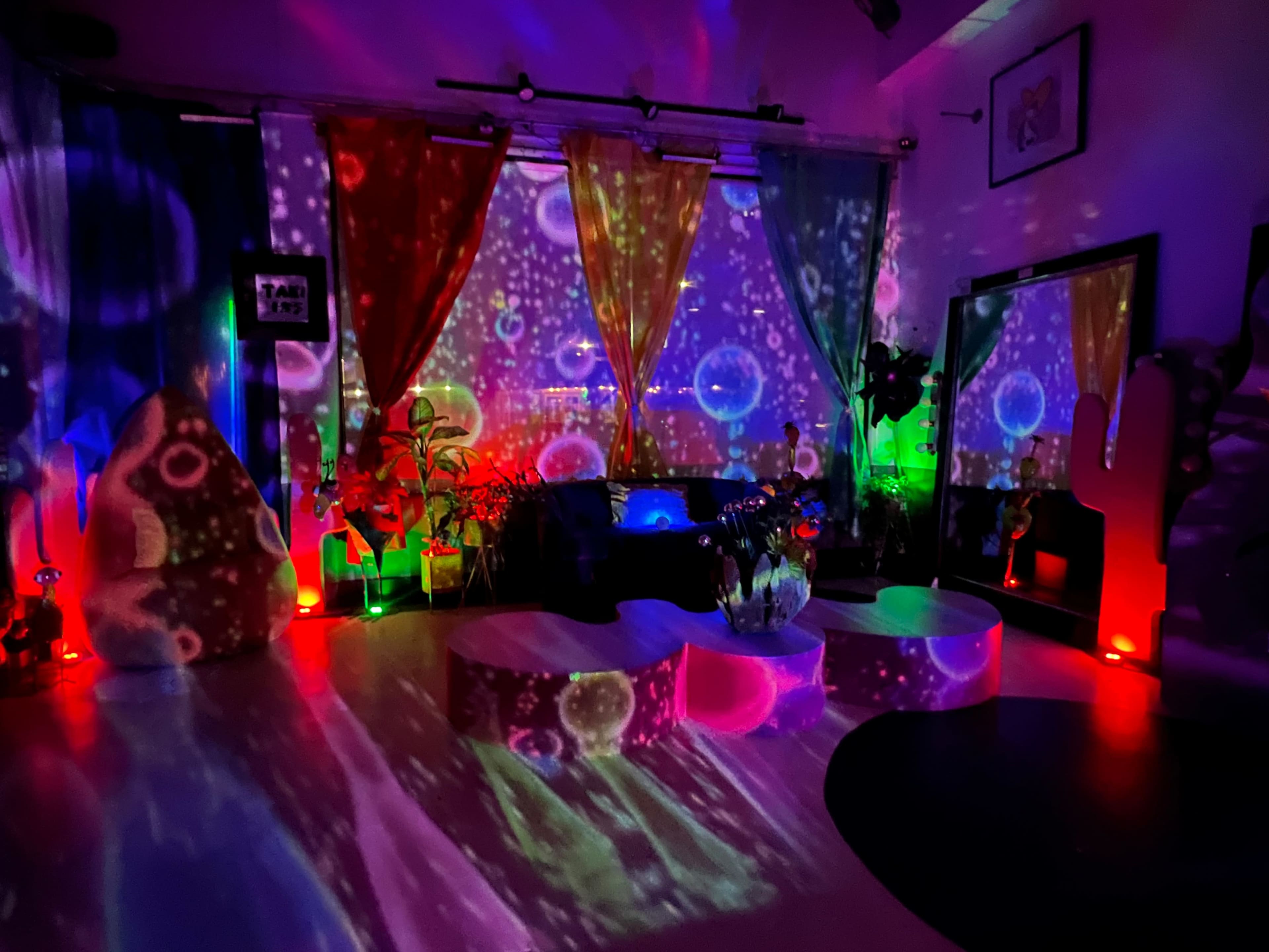 The room features colorful lights projecting patterns on the walls and furniture, creating a vibrant atmosphere.