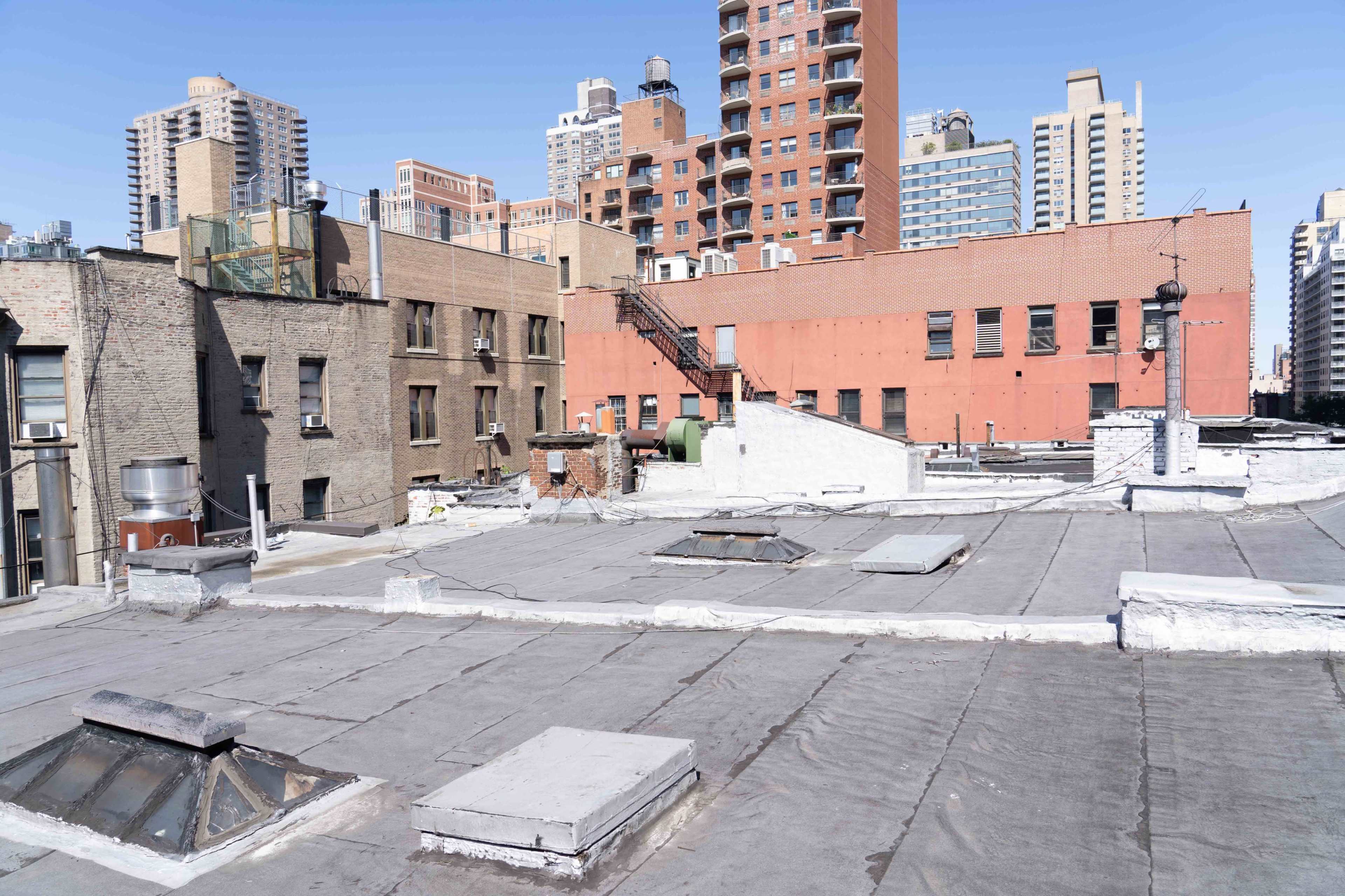 A view of urban rooftops with buildings in the background under a clear sky.