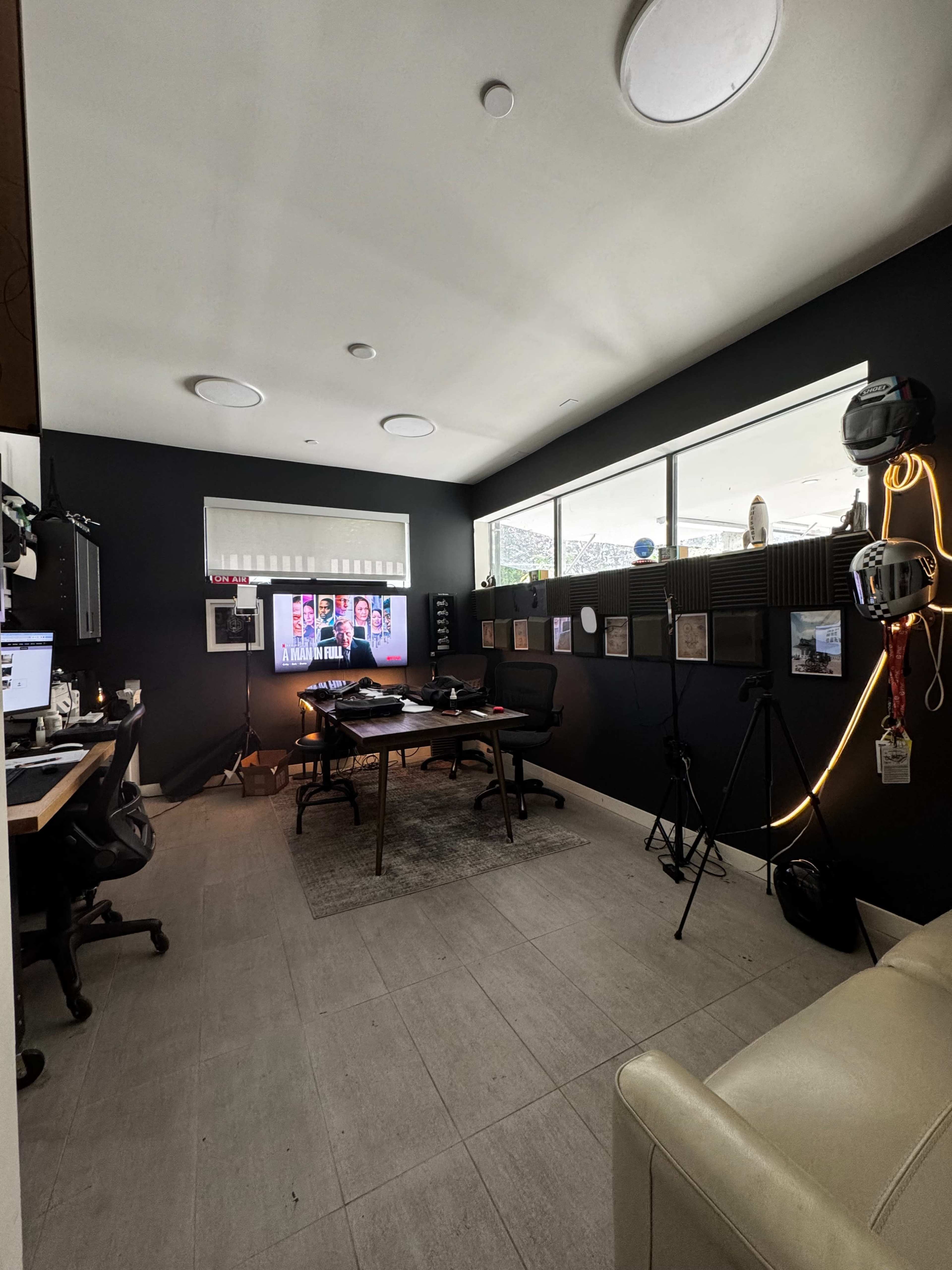 A modern office space with two desks, a large screen on the wall, and various decorations, including framed pictures and a tripod.