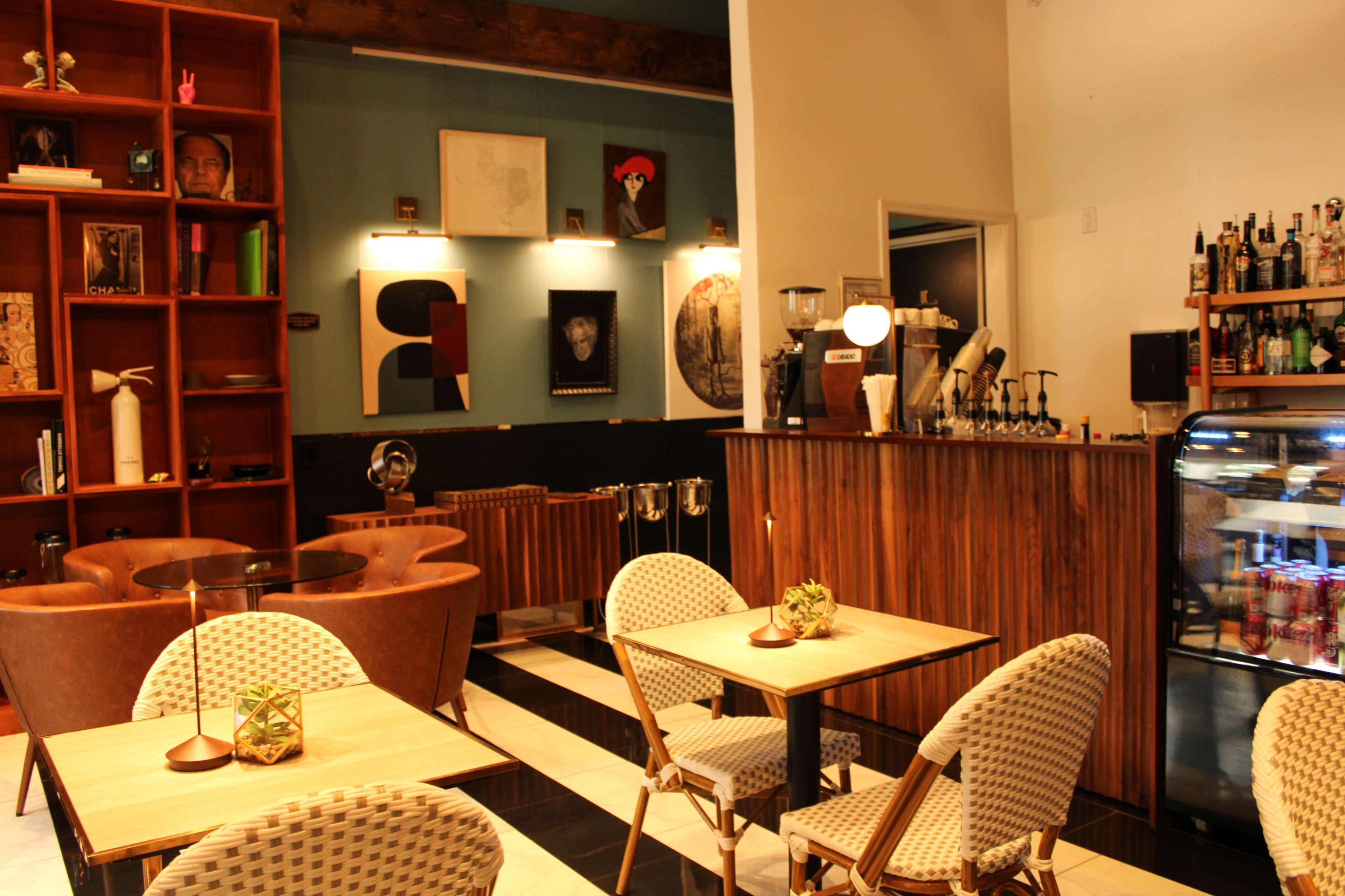 A contemporary café interior with wooden shelves, seating areas, and a display counter for beverages.
