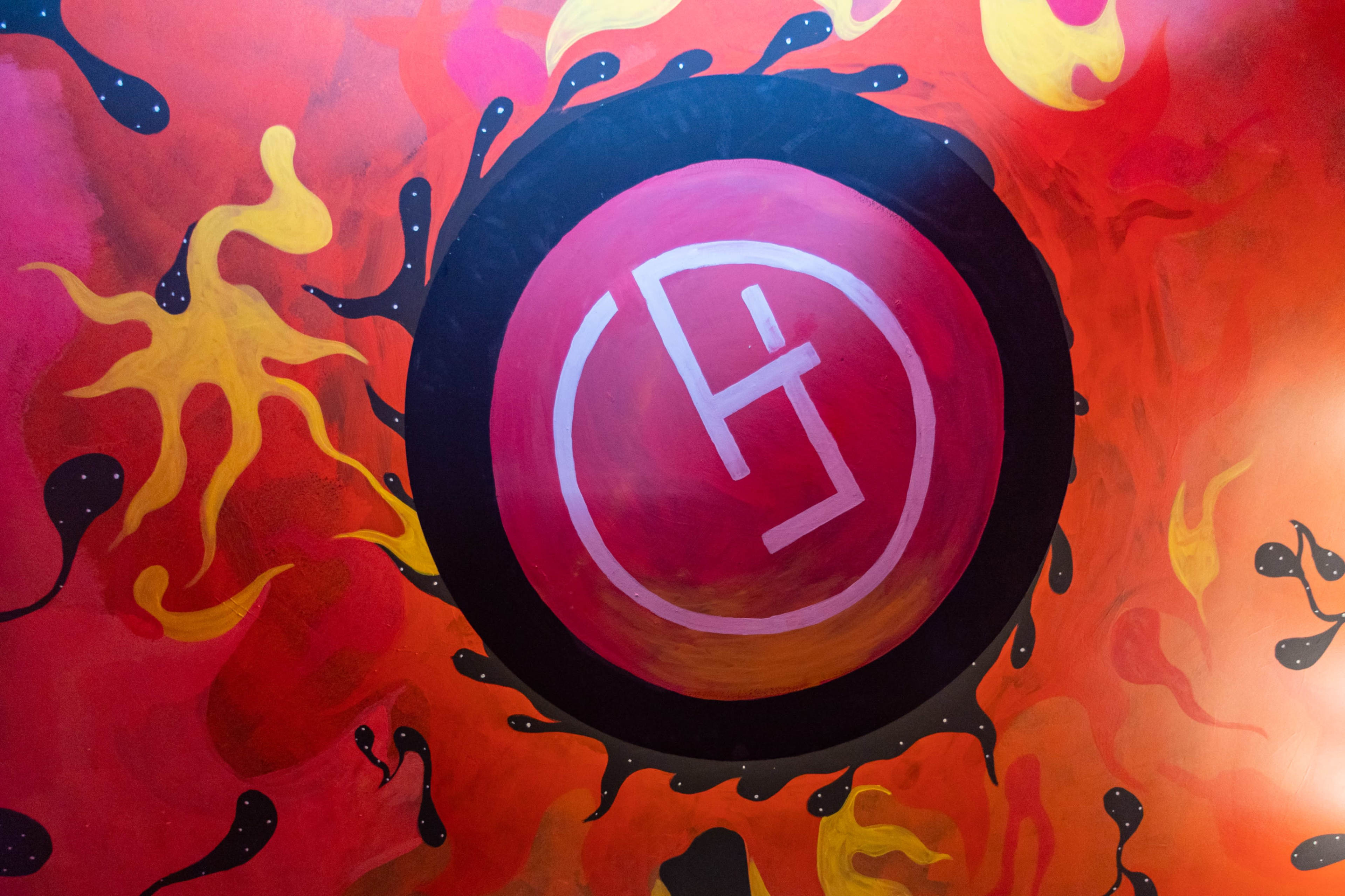 The image features a circular design with a symbol in the center, surrounded by vibrant orange and yellow patterns resembling flames.
