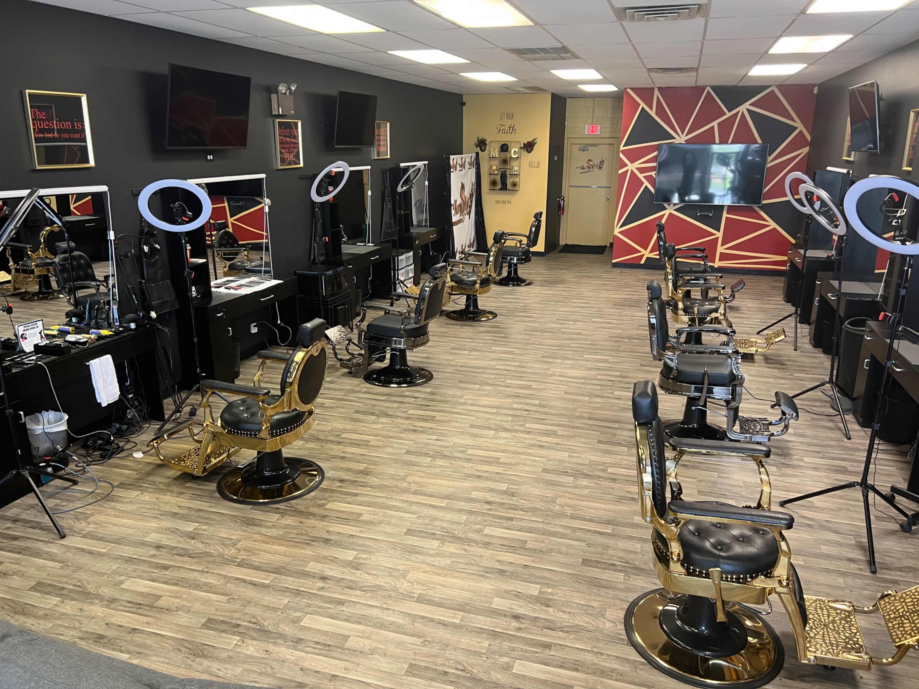 A barber shop interior with multiple styling stations and mirrors, featuring golden barber chairs and lighting equipment arranged neatly.