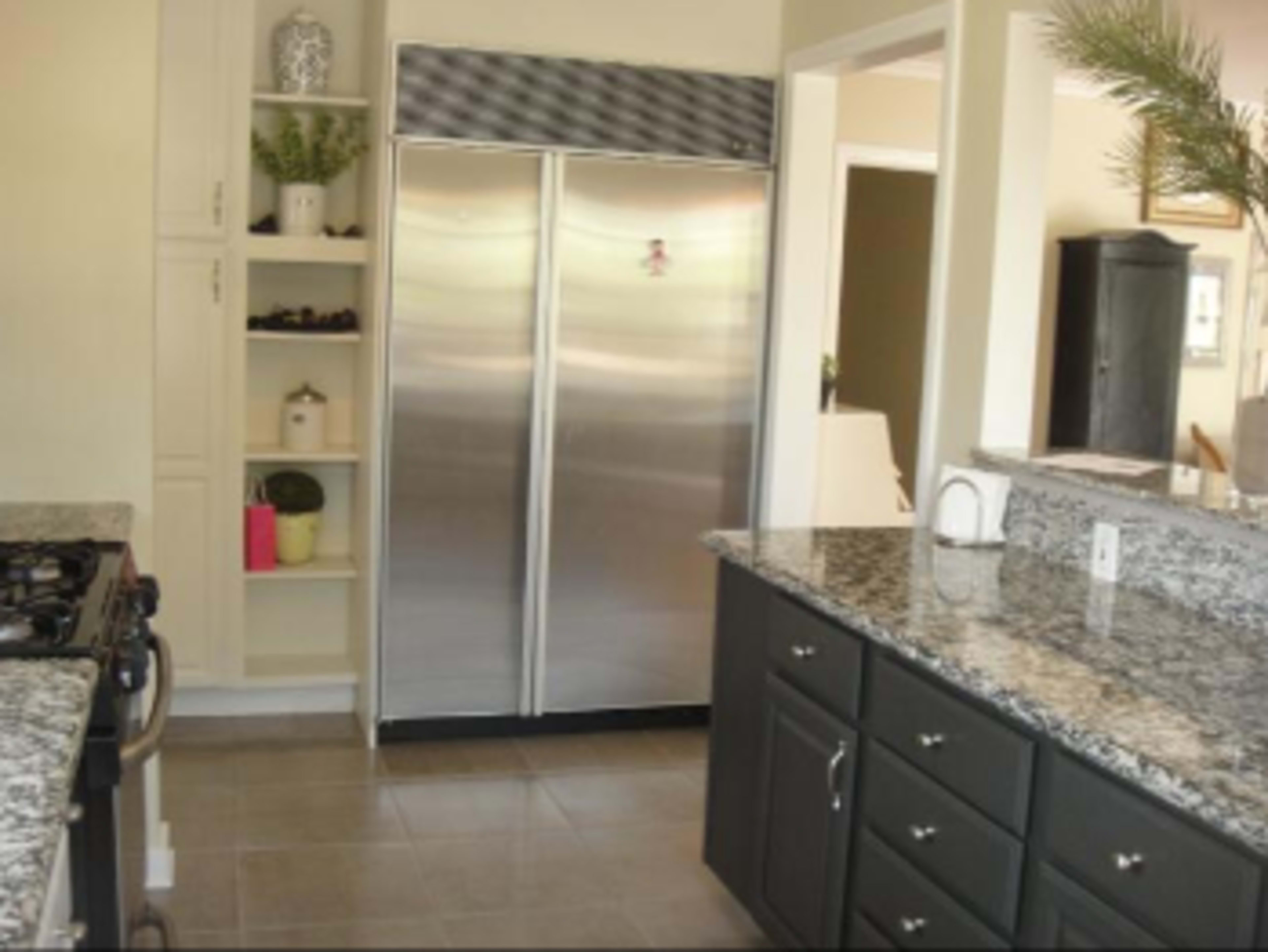 A kitchen with stainless steel double doors for a refrigerator, granite countertops, and dark cabinetry.
