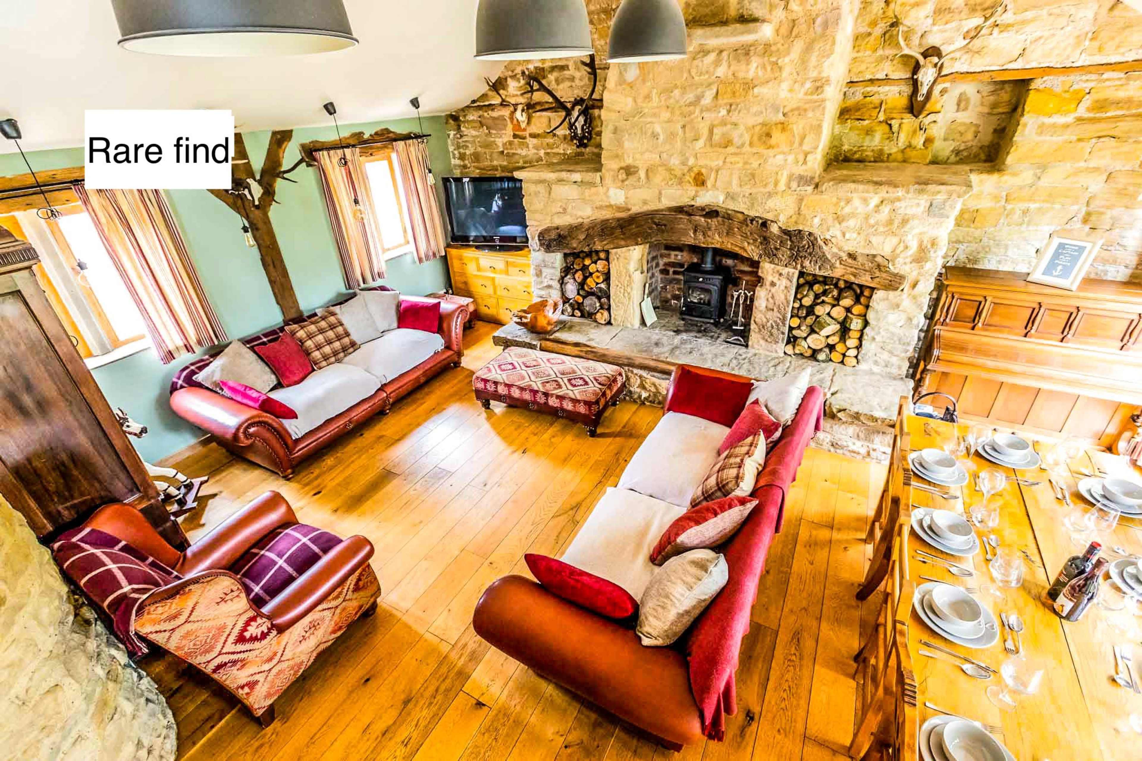 A spacious living room with a stone fireplace, wooden furniture, and a dining area set for a meal.