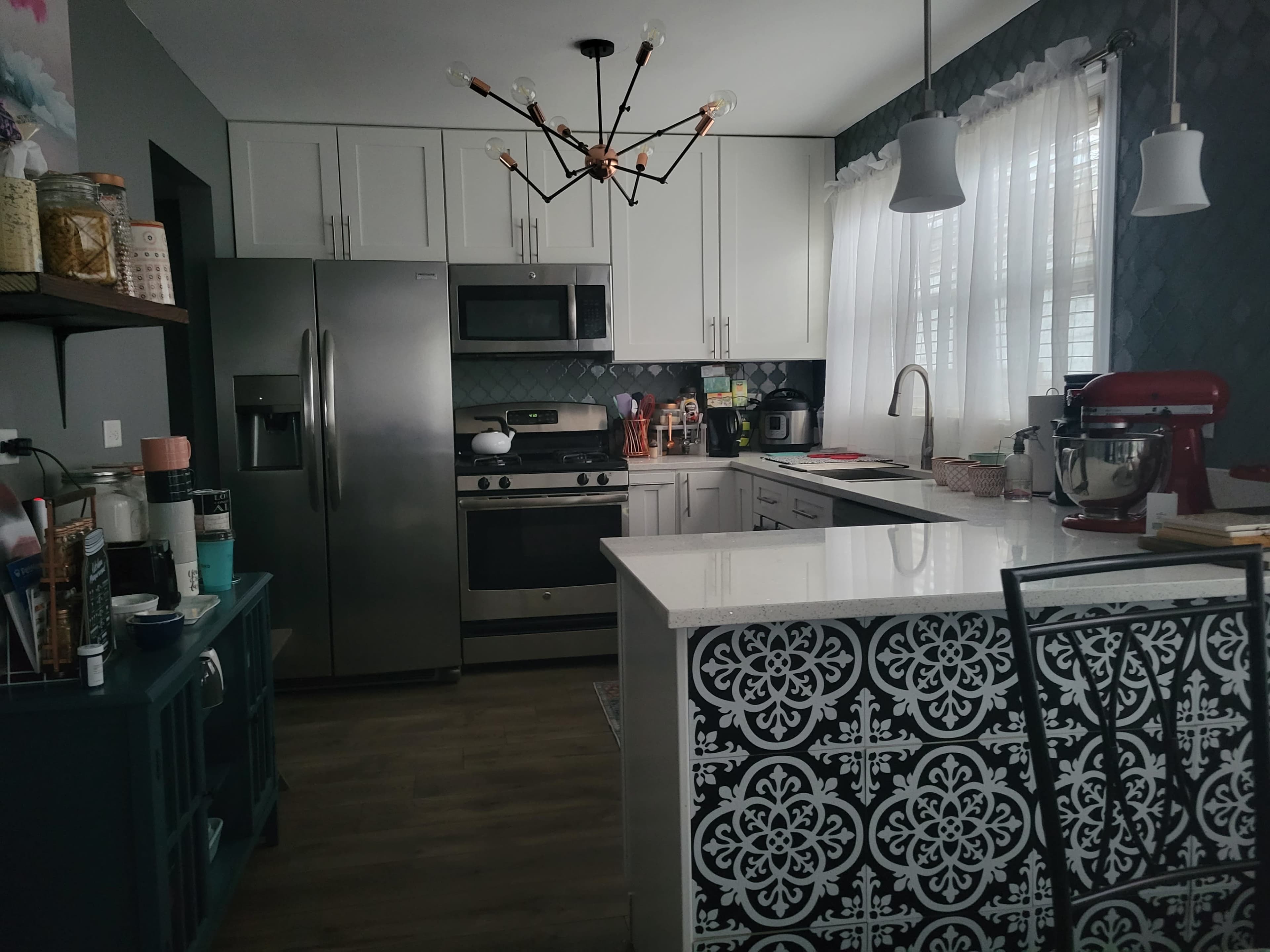 A modern kitchen with stainless steel appliances, a white countertop, and a patterned black and white kitchen island.