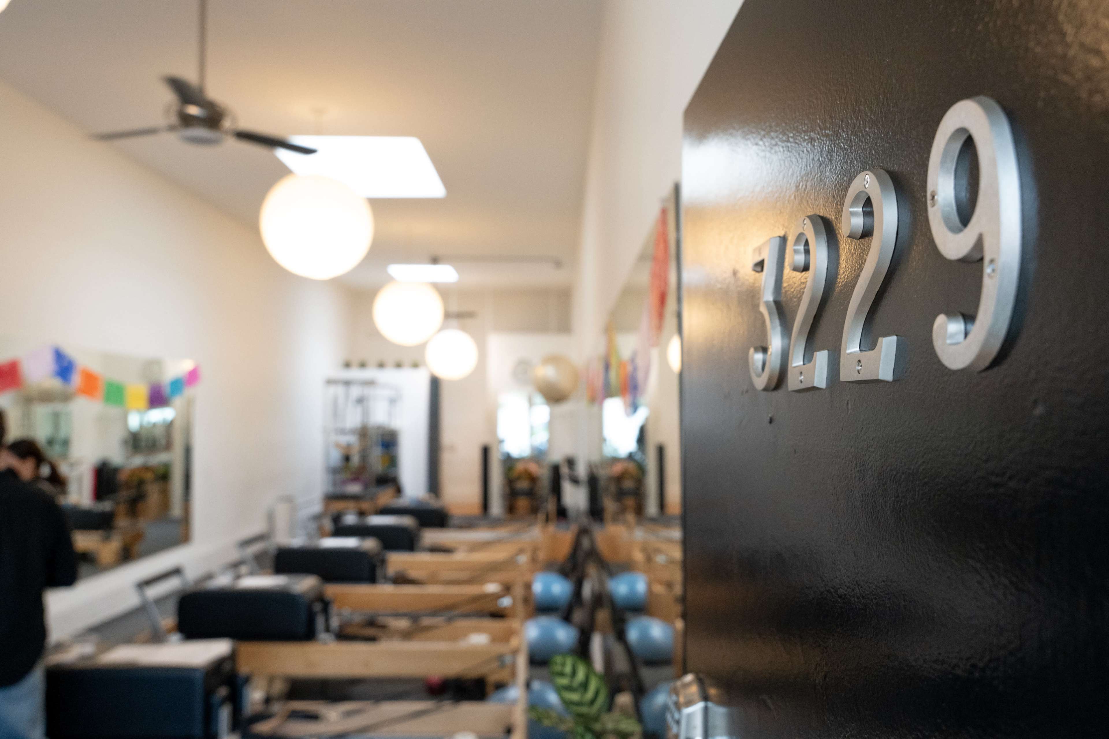 A studio entrance with the number "3229" on a black door, leading into a bright fitness space filled with equipment and decor.