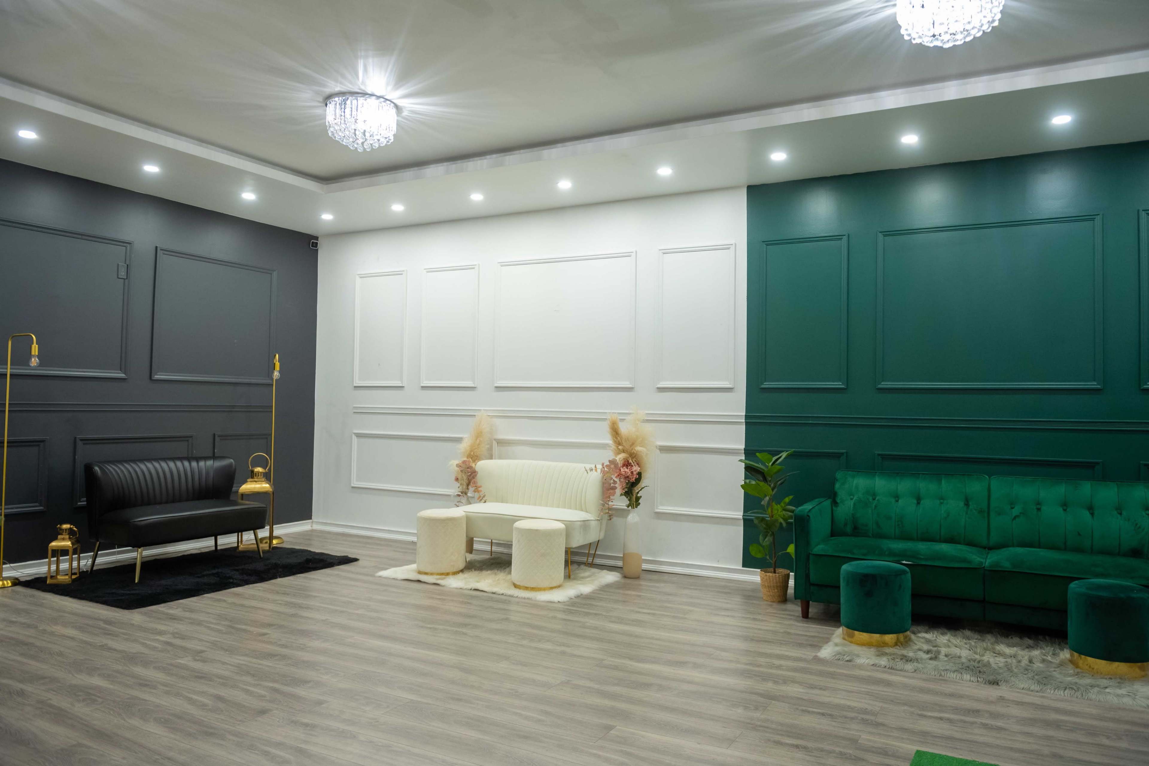 A modern living space featuring a black leather sofa, a white loveseat, a dark green velvet sofa, and decorative elements against a backdrop of paneled walls in various colors.