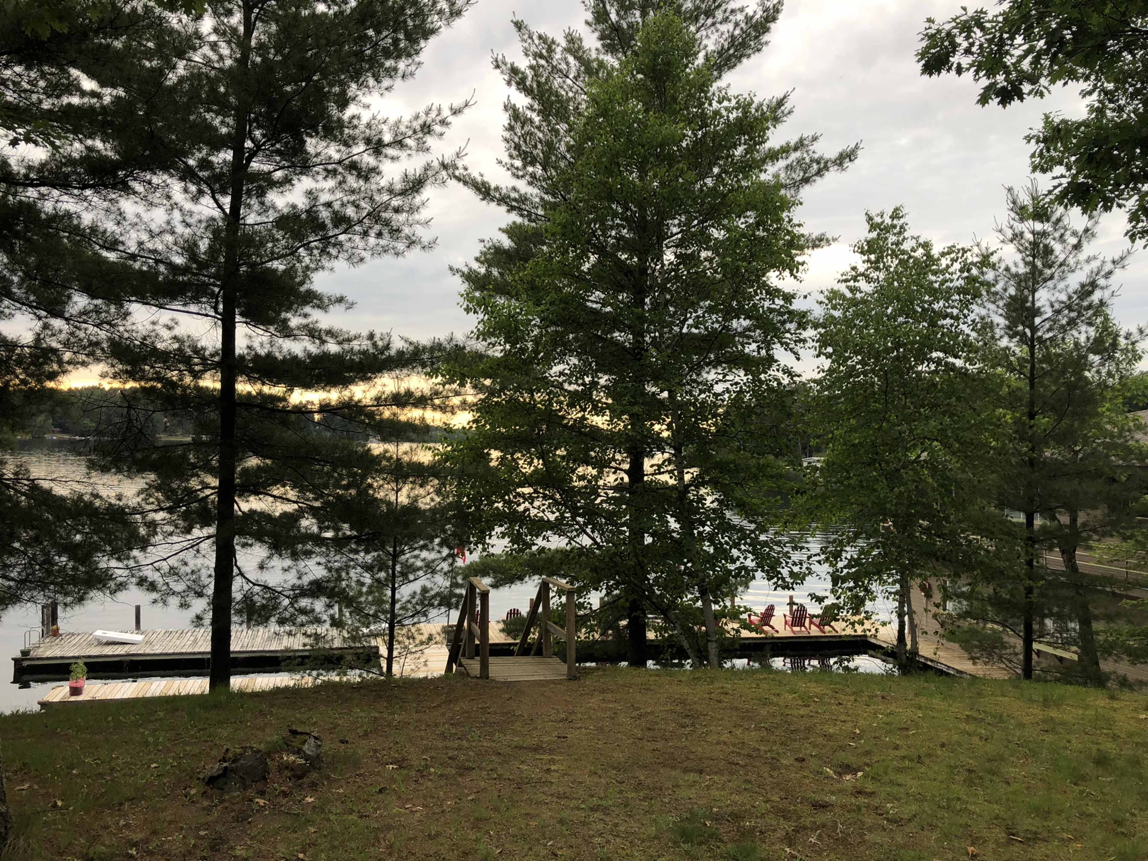 A view of a lake framed by trees, with a wooden dock and seating area in the background.