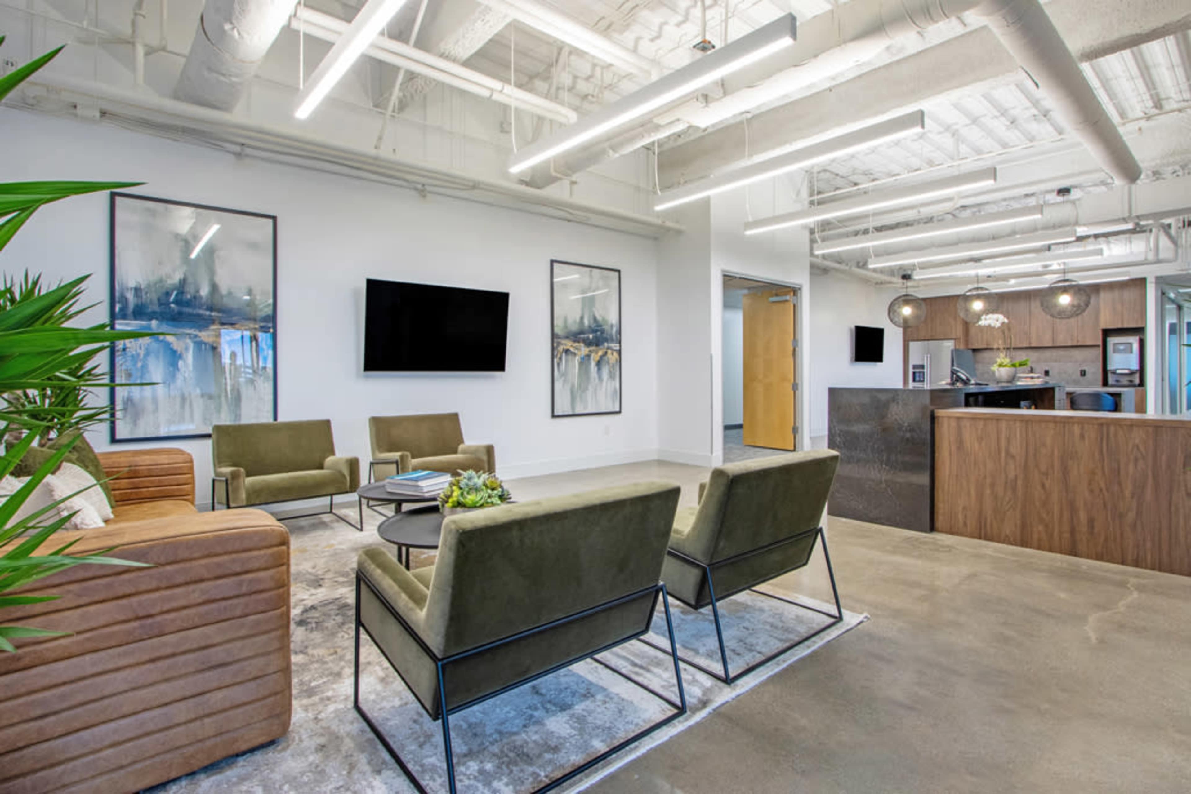 The image shows a modern office reception area with green chairs, a wooden reception desk, and abstract artwork on the walls.
