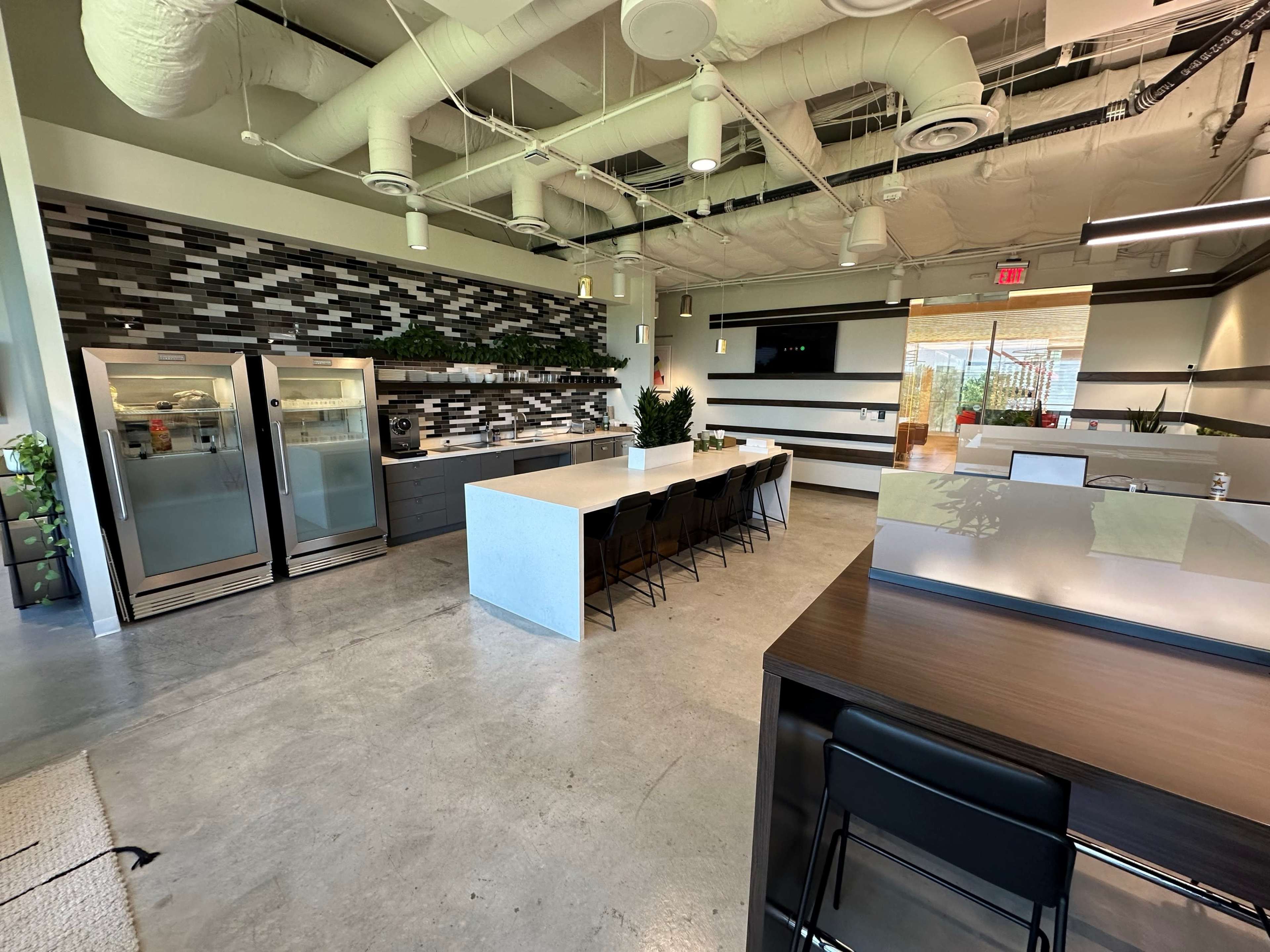 A modern kitchen area with stainless steel appliances, a large island, and seating for eight, all set against a backdrop of gray and green decor.