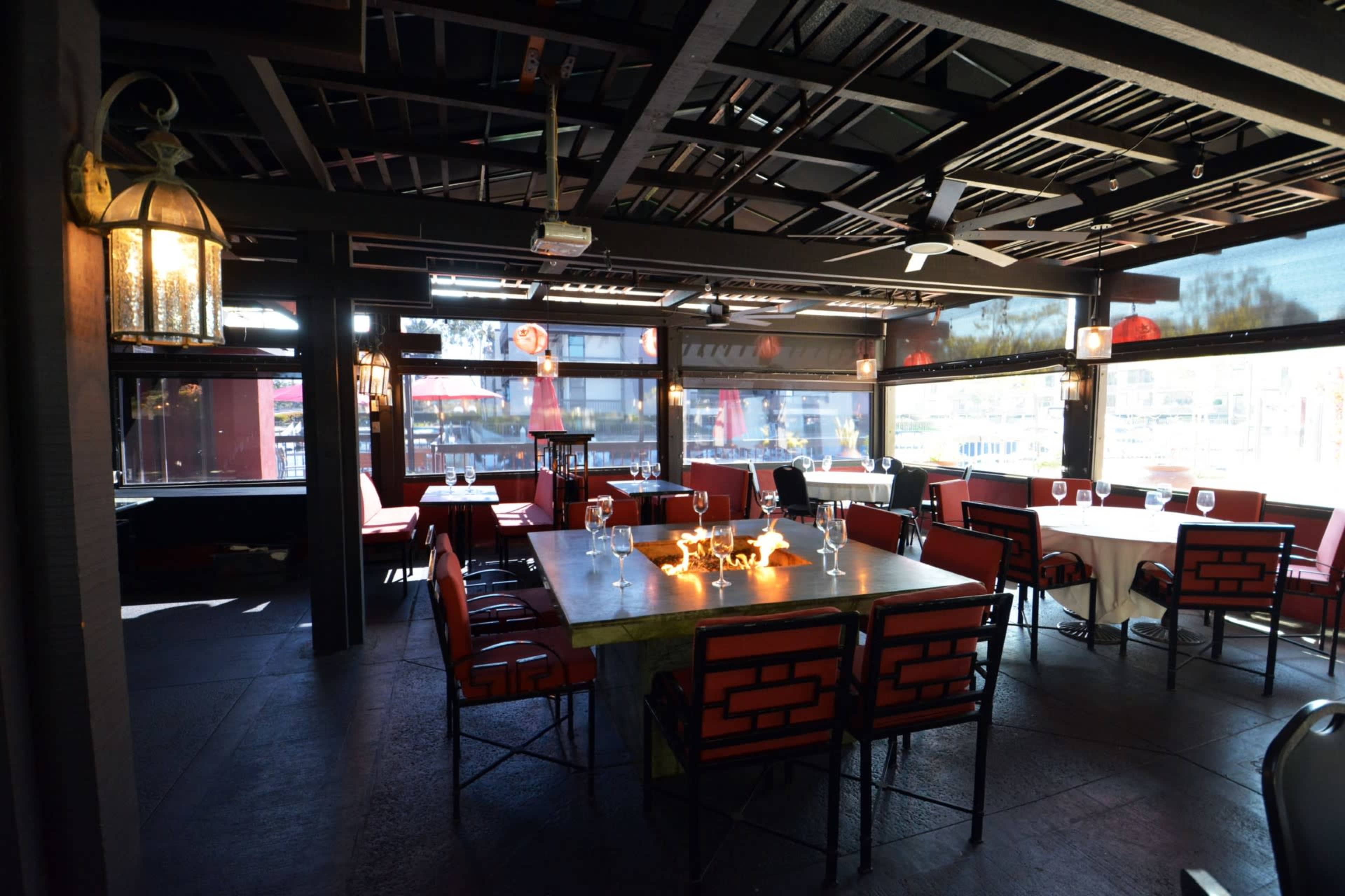 A dining area in a restaurant with several tables set for guests and large windows providing natural light.