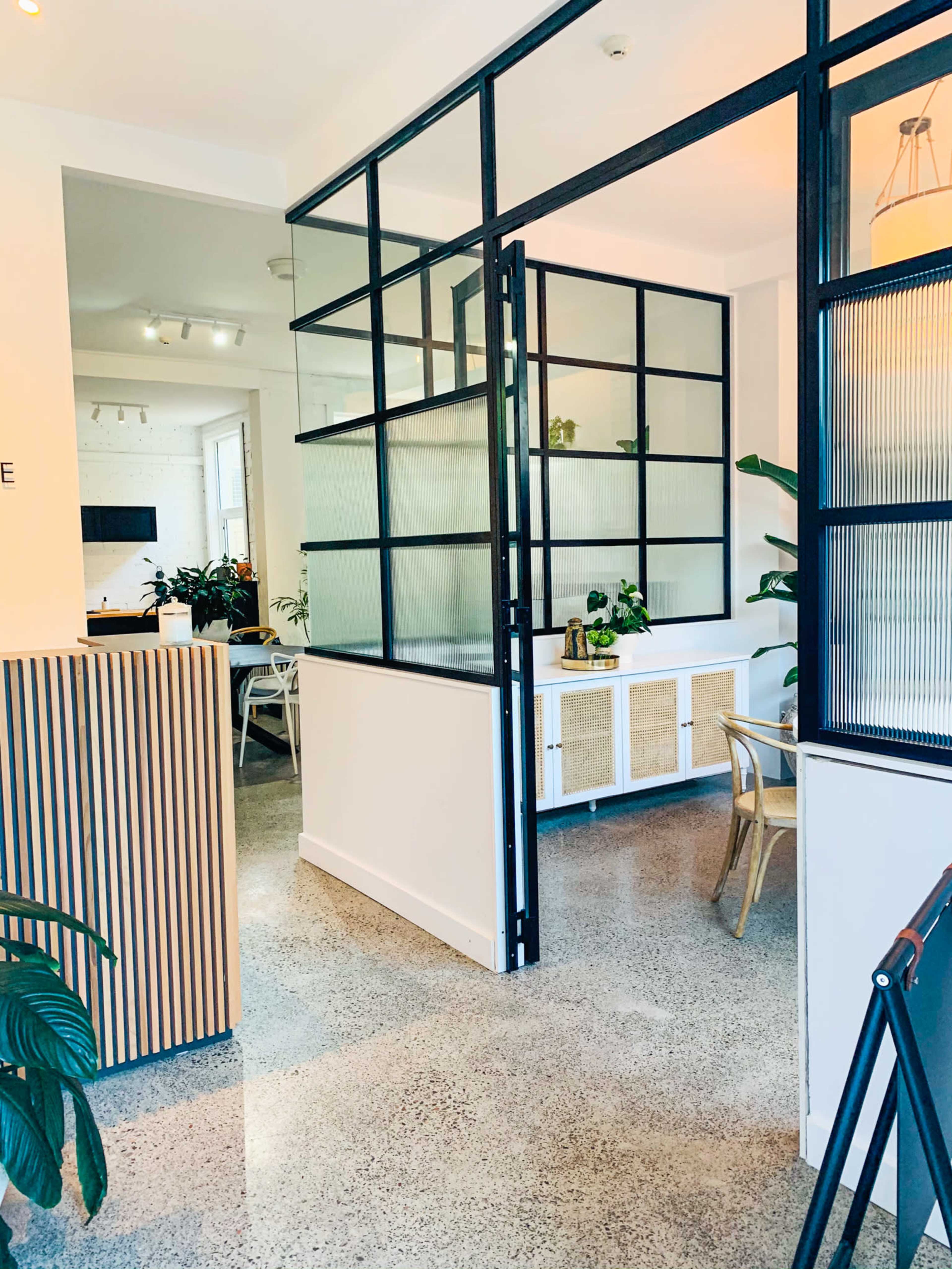 A modern interior space featuring a glass partition, plants, and a polished concrete floor.