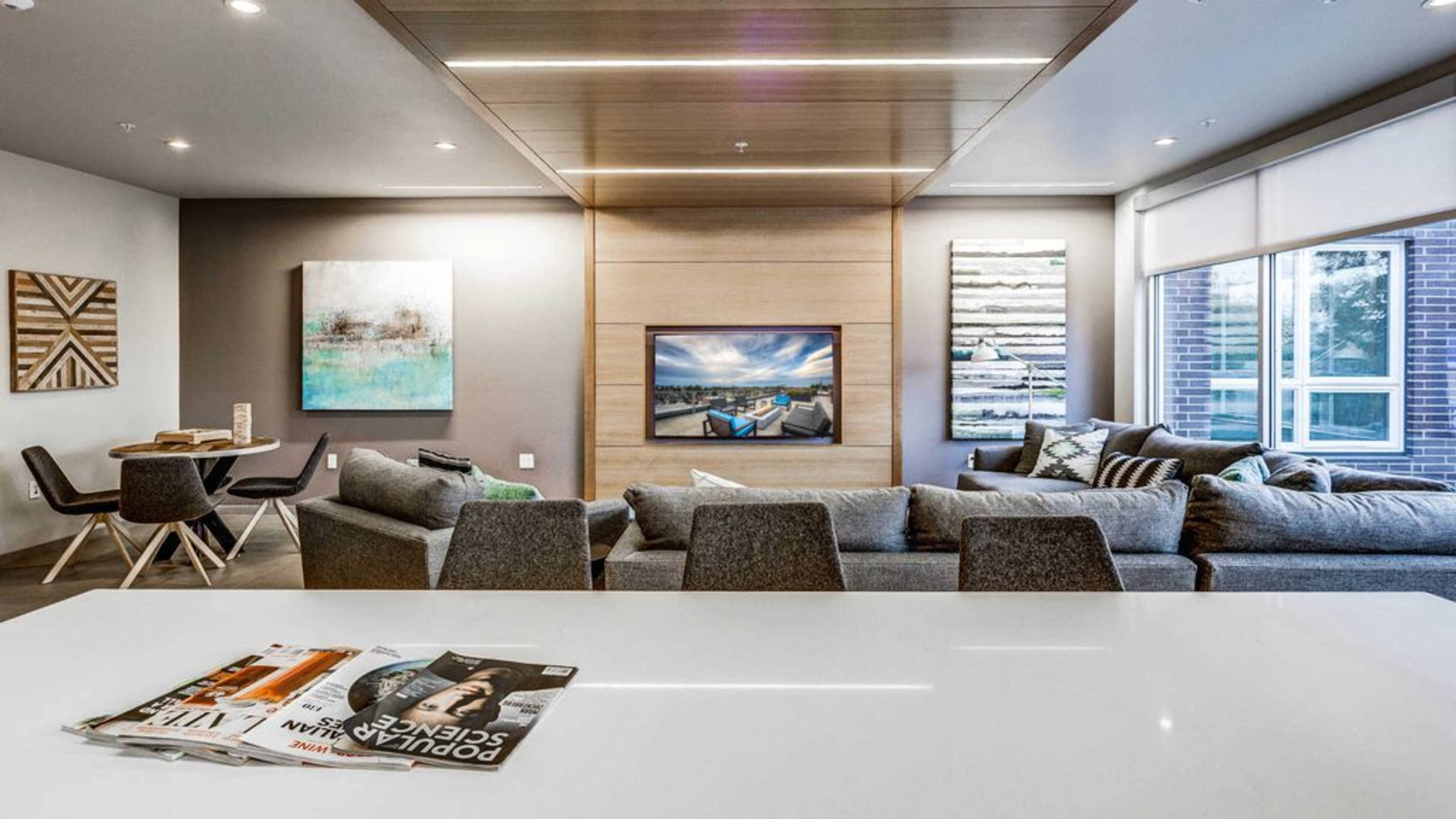 A modern living room with a large sectional sofa, a mounted television, and abstract artwork on the walls.
