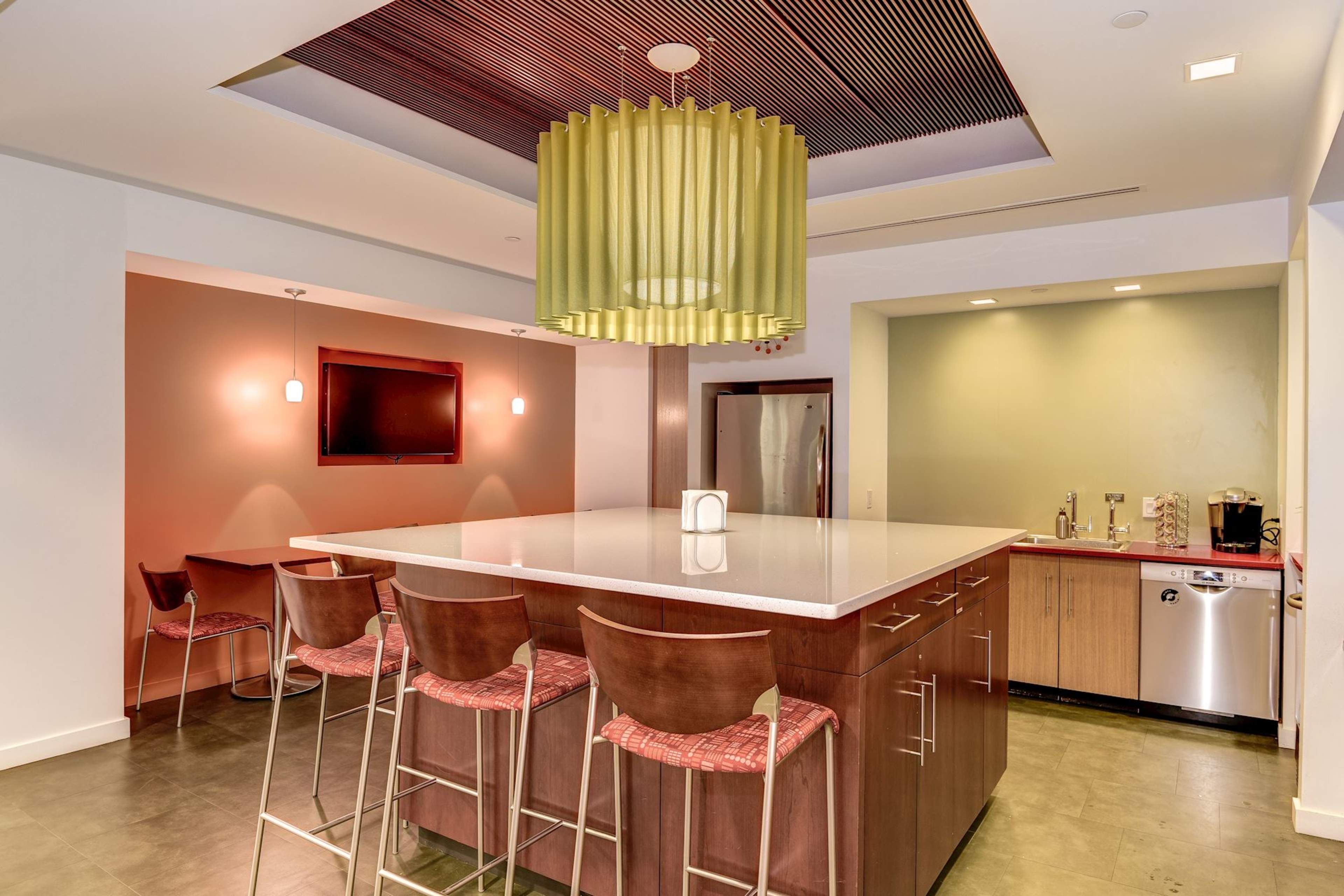The image showcases a modern kitchen with a central island, bar seating, and a large pendant light overhead.