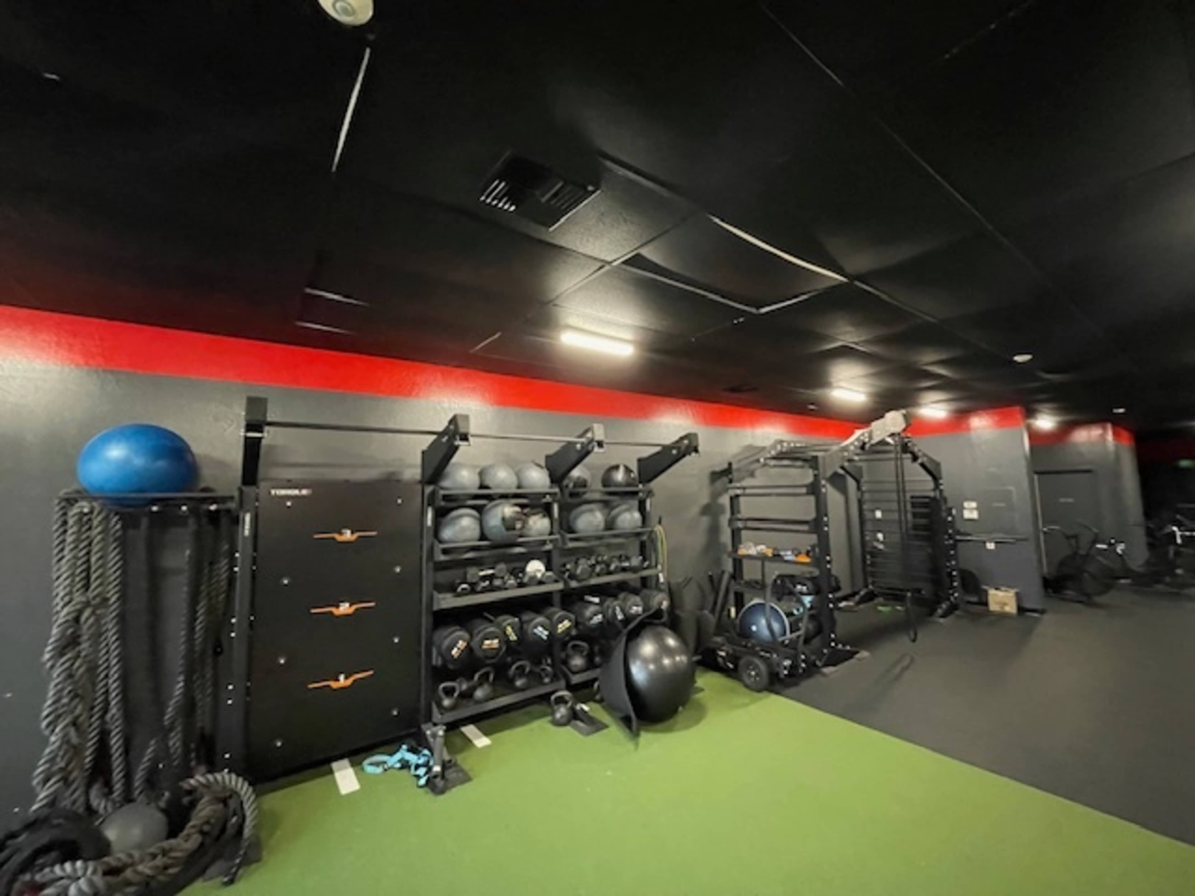 A fitness area with wall-mounted storage for exercise equipment, including medicine balls and kettlebells, along with workout ropes on the floor.