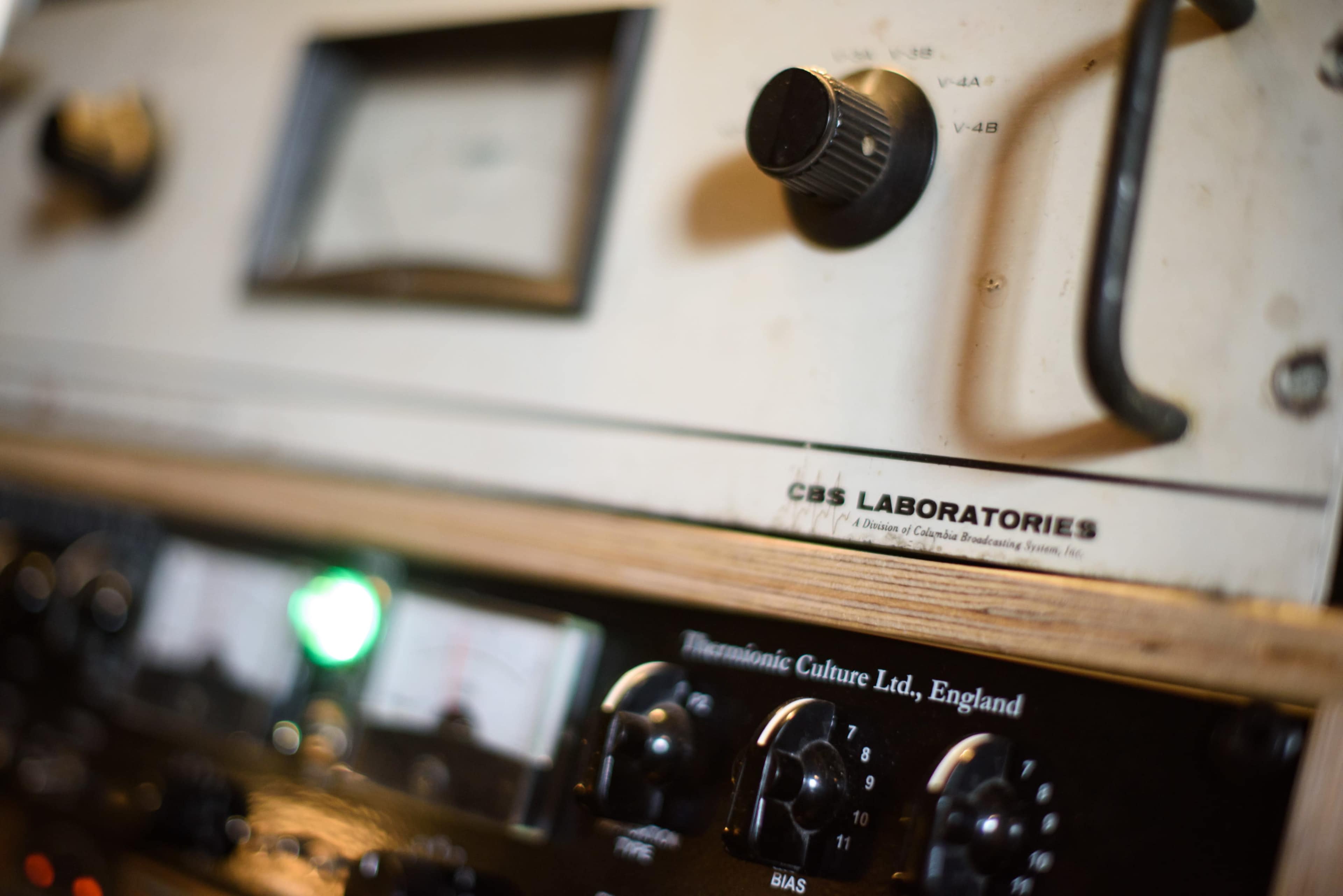 The image shows a close-up of a vintage audio mixing console with various knobs and meters, labeled "CBS Laboratories" and "Thermionic Culture Ltd, England."