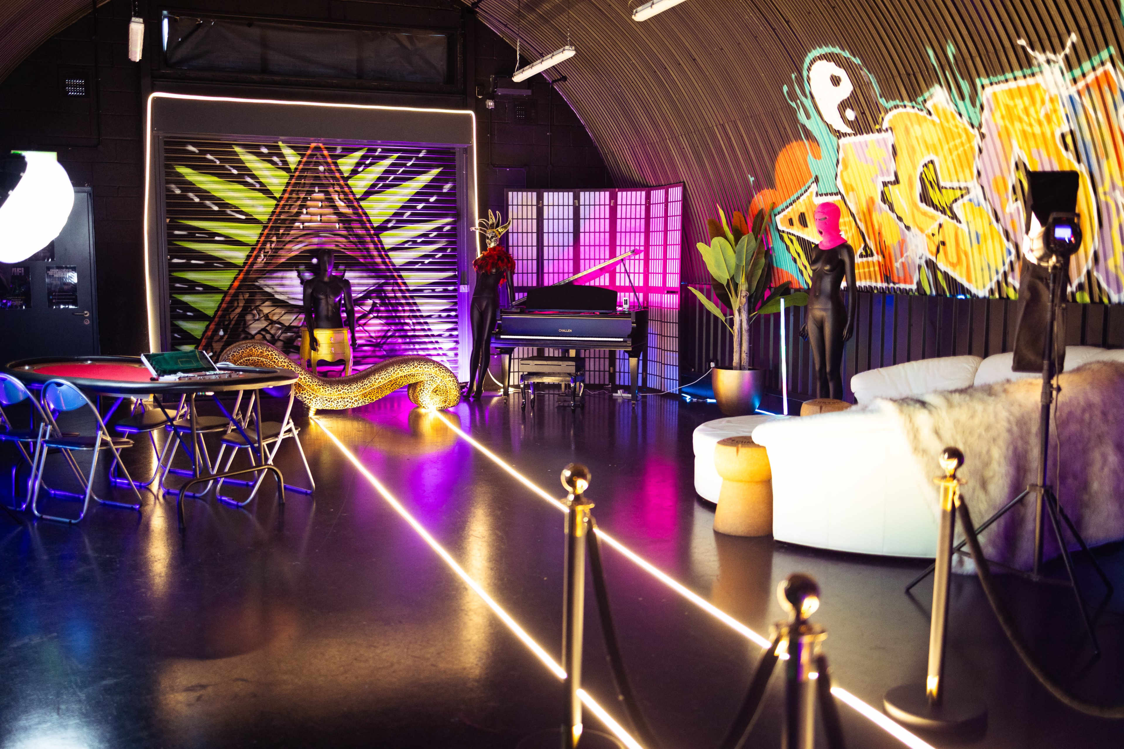 The scene features a stylish, modern lounge area with a piano, seating, and vibrant neon lights, set against a backdrop of colorful graffiti and artistic decorations.