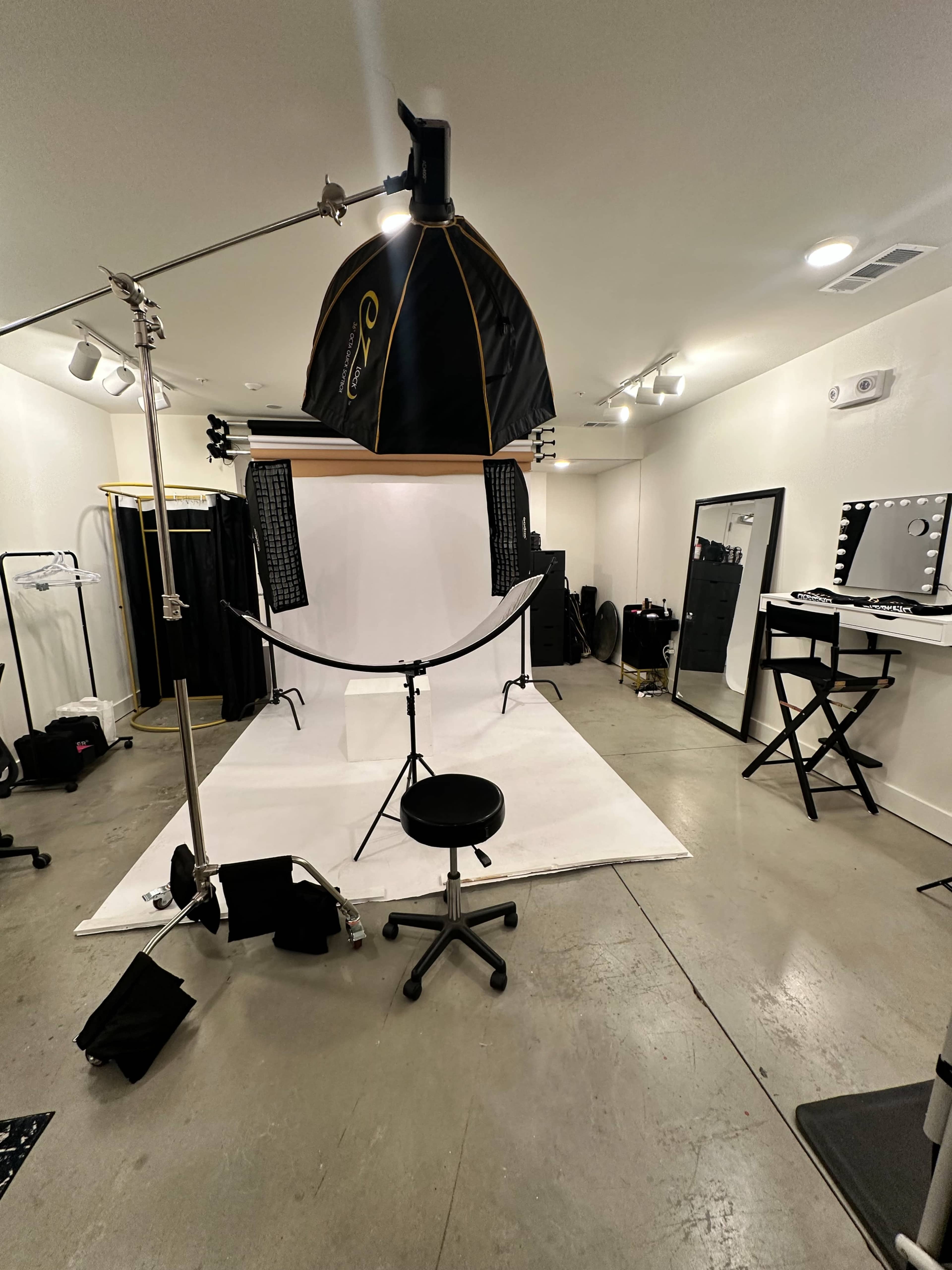 The image shows a photography studio equipped with a backdrop, lighting setup, and various furniture for shooting and dressing.