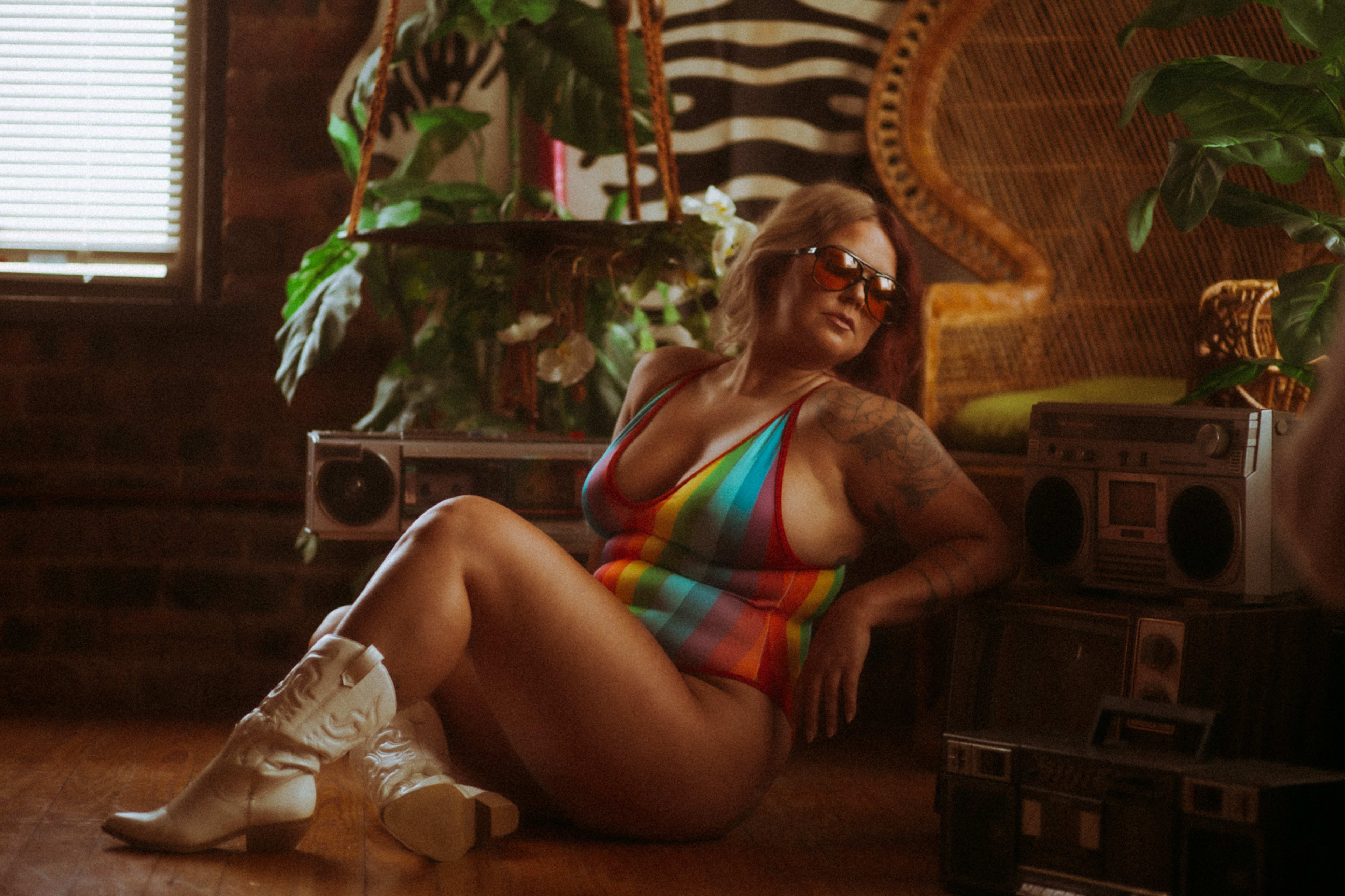 A woman in a rainbow bathing suit lounging on the floor.