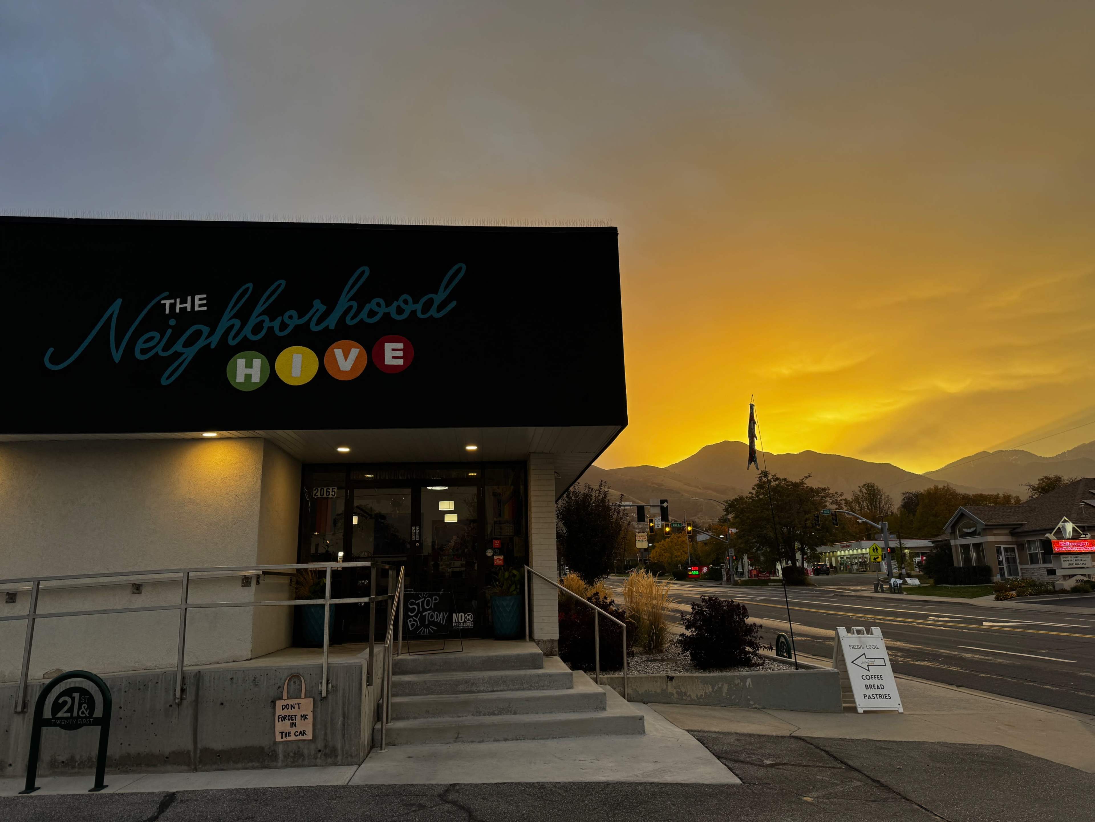 The image shows a building labeled "The Neighborhood Hive" with a sunset backdrop illuminating the sky in orange and yellow hues.