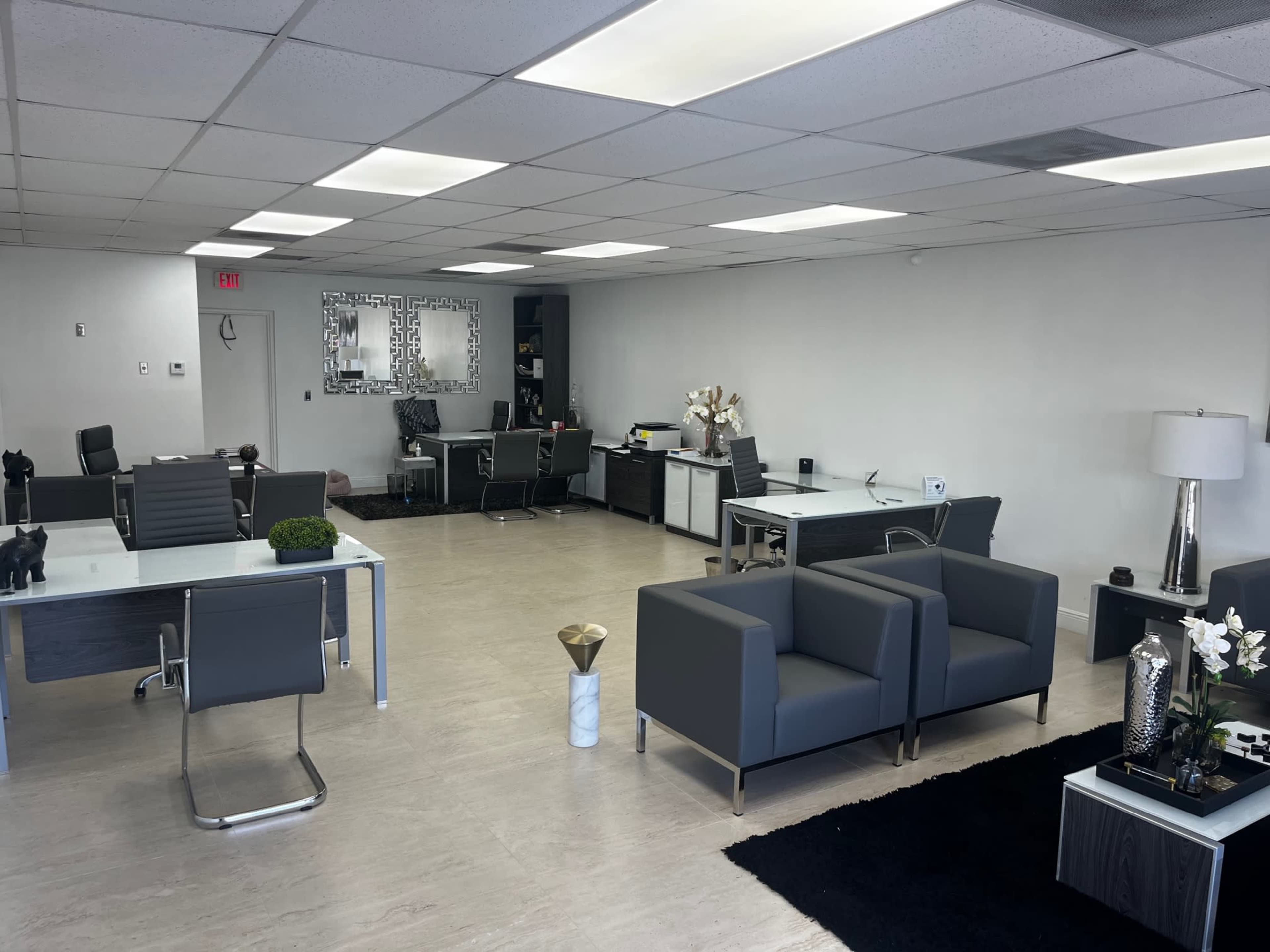 A modern office space with several desks, chairs, and decorative elements, arranged in an open layout.