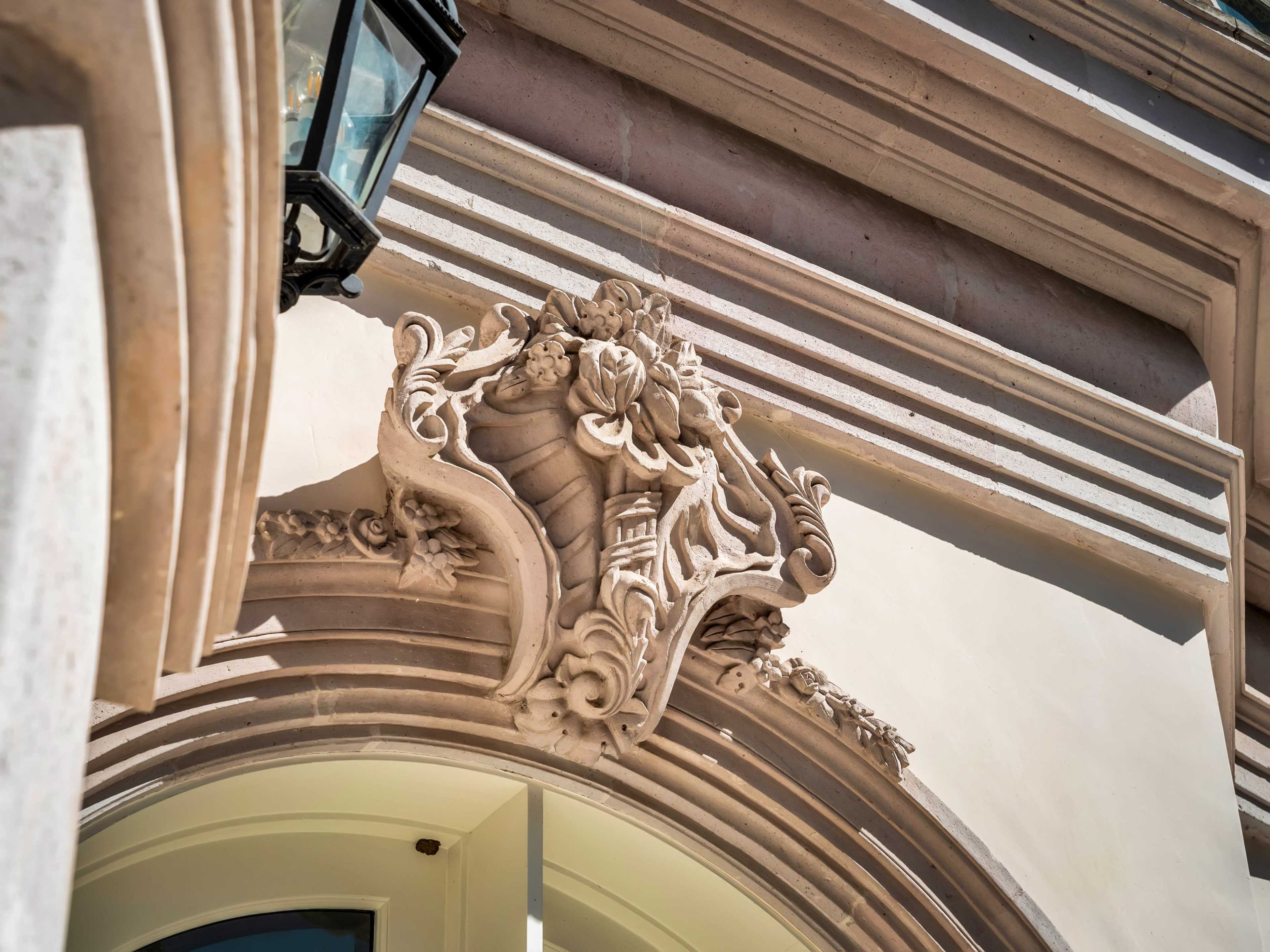 An intricately detailed stone relief depicting decorative elements on the facade of a building, accompanied by a lantern.
