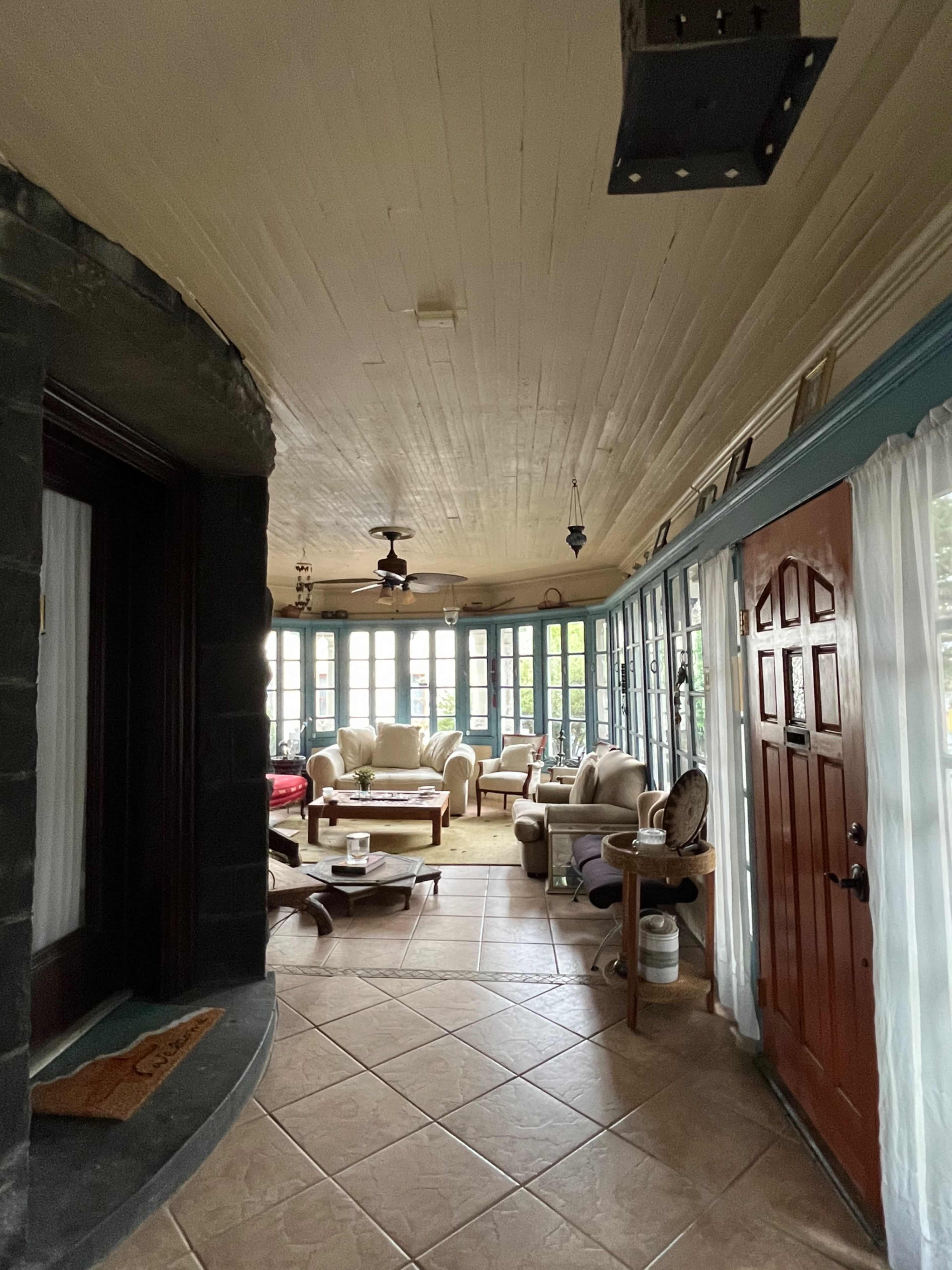 A sunroom with large windows, a seating area, and a door leading outside.
