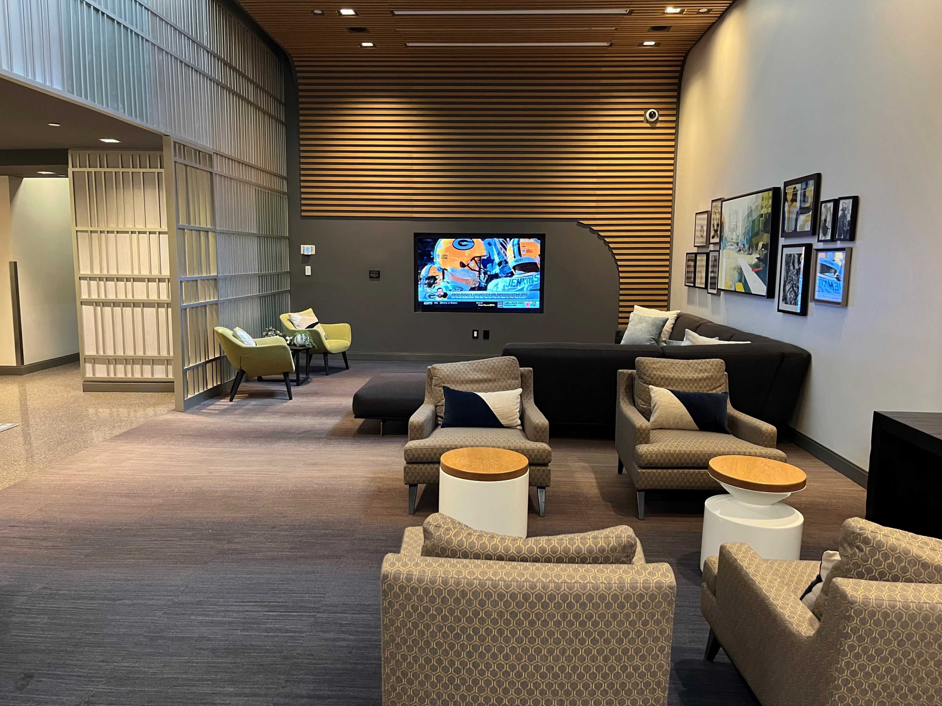 The image features a modern lounge area with seating, a television, and decorative wall art.
