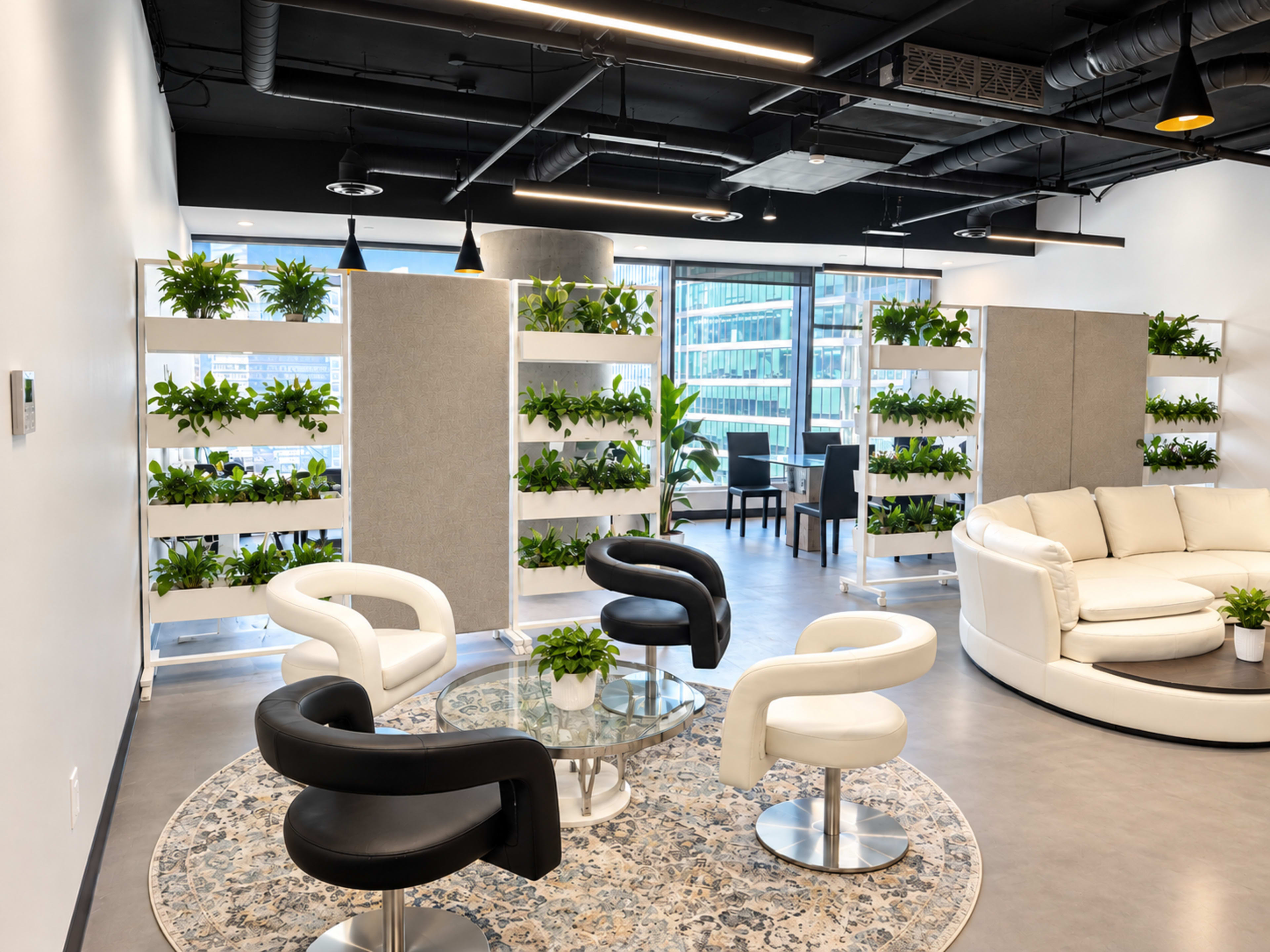 The image features a modern office lounge area with white and black chairs arranged around a glass table, surrounded by green plants on shelf partitions and a circular rug.