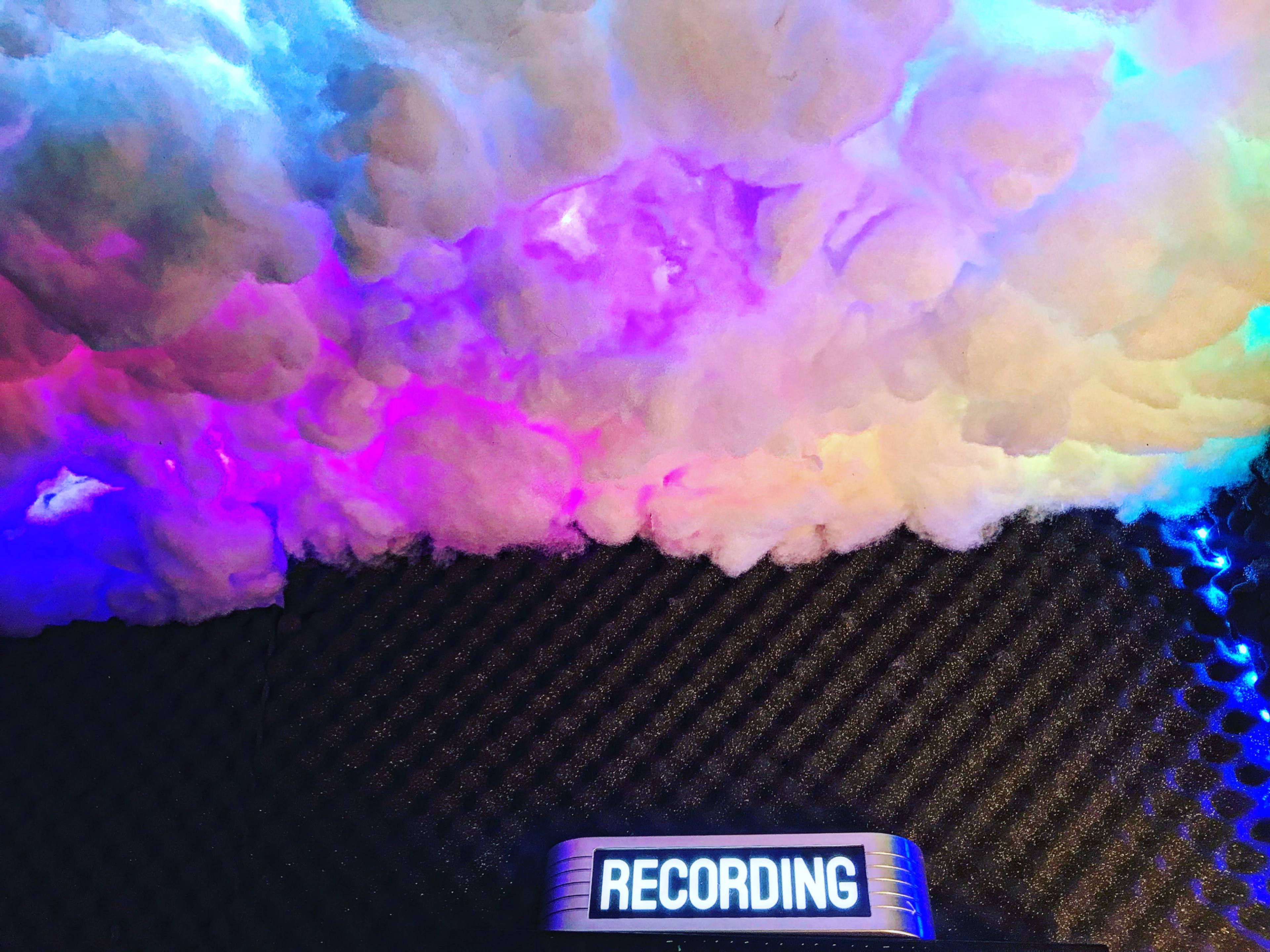 A colorful cloud-like installation is positioned above a rectangular sign that reads "RECORDING."