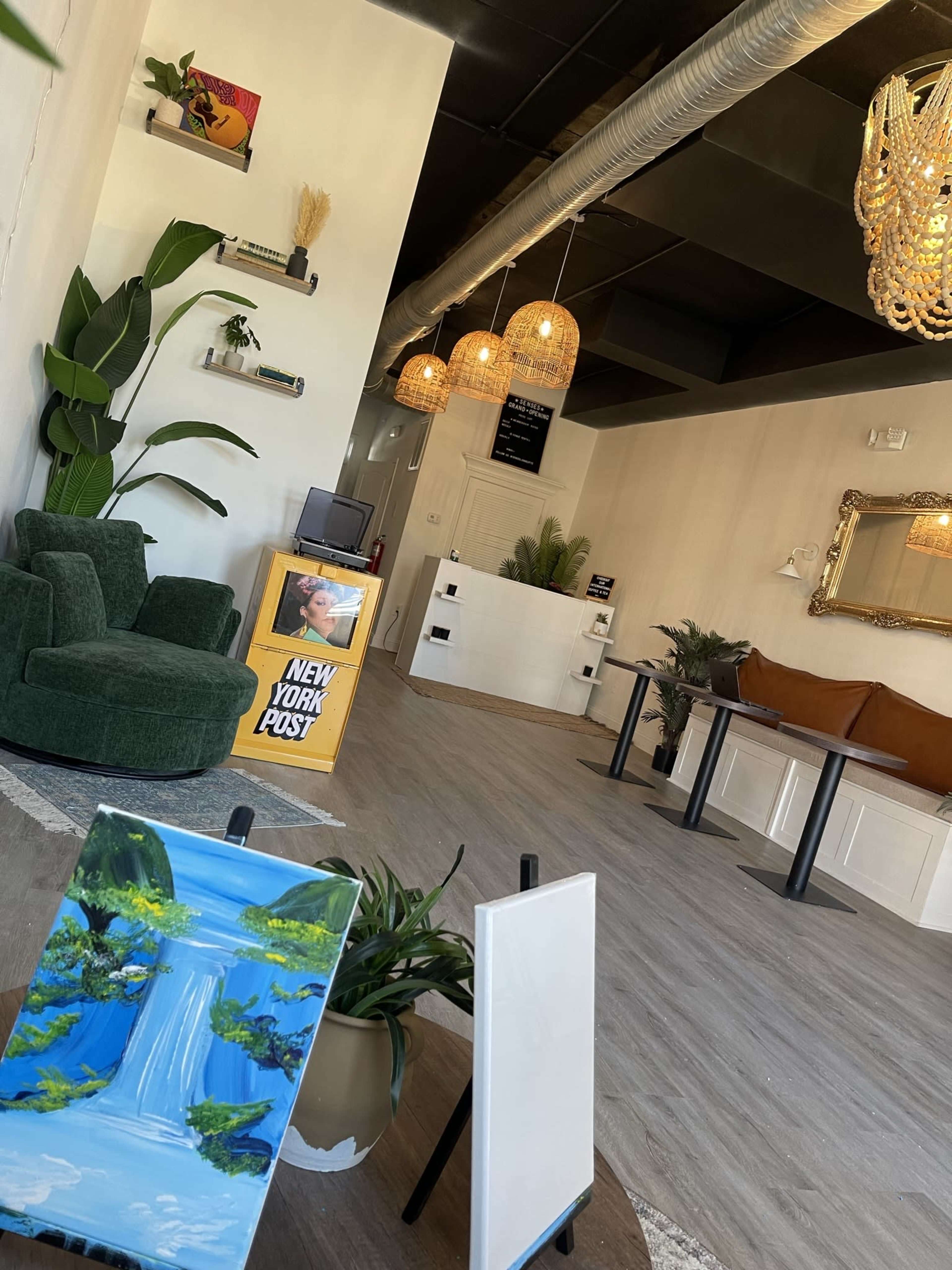 A modern interior of a cafe or studio with green furniture, decorative plants, and pendant lighting.