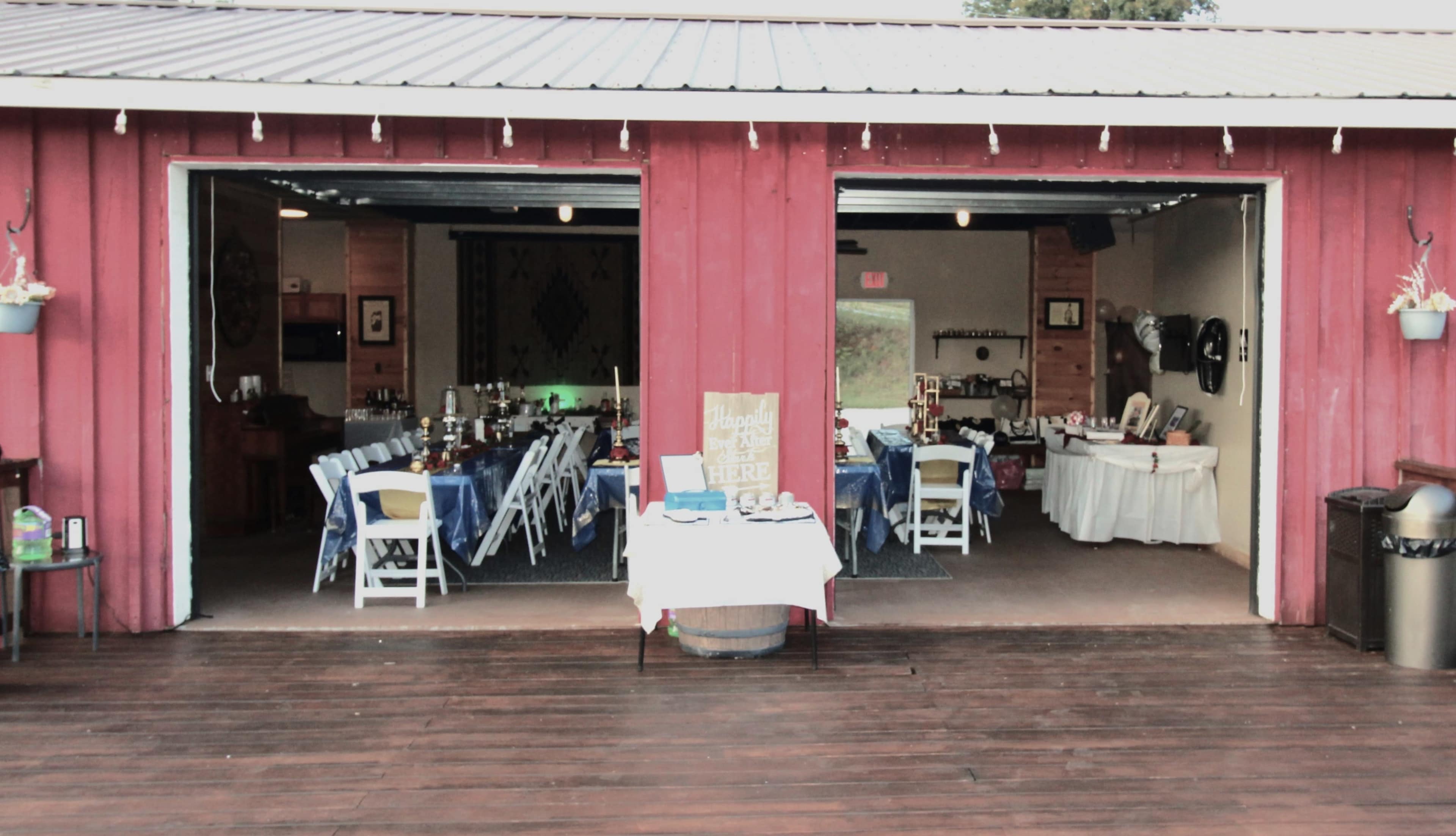 The image shows a rustic venue with two open sections filled with dining tables, decor, and festive lighting.