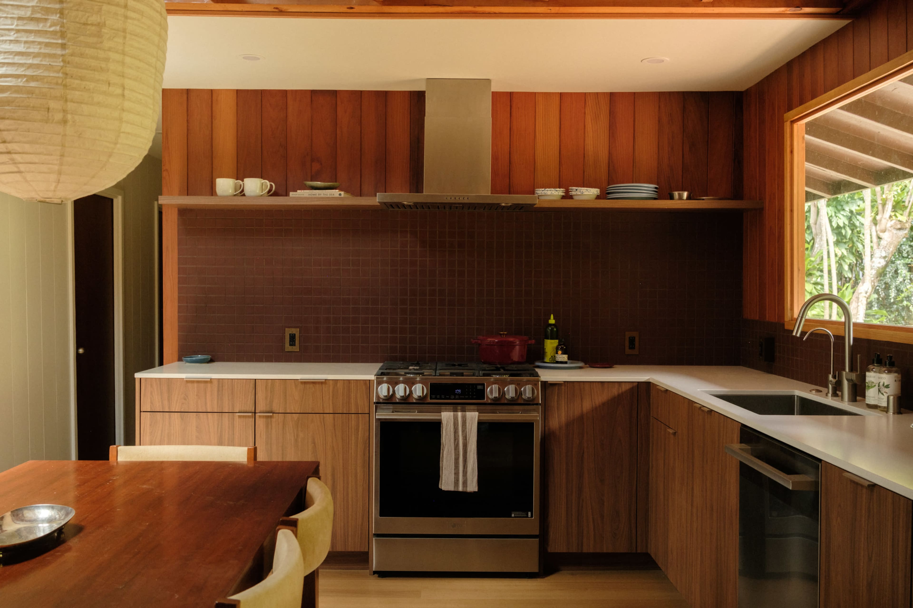 The image shows a modern kitchen with wooden cabinets, a white countertop, and a gas stove integrated into the design.