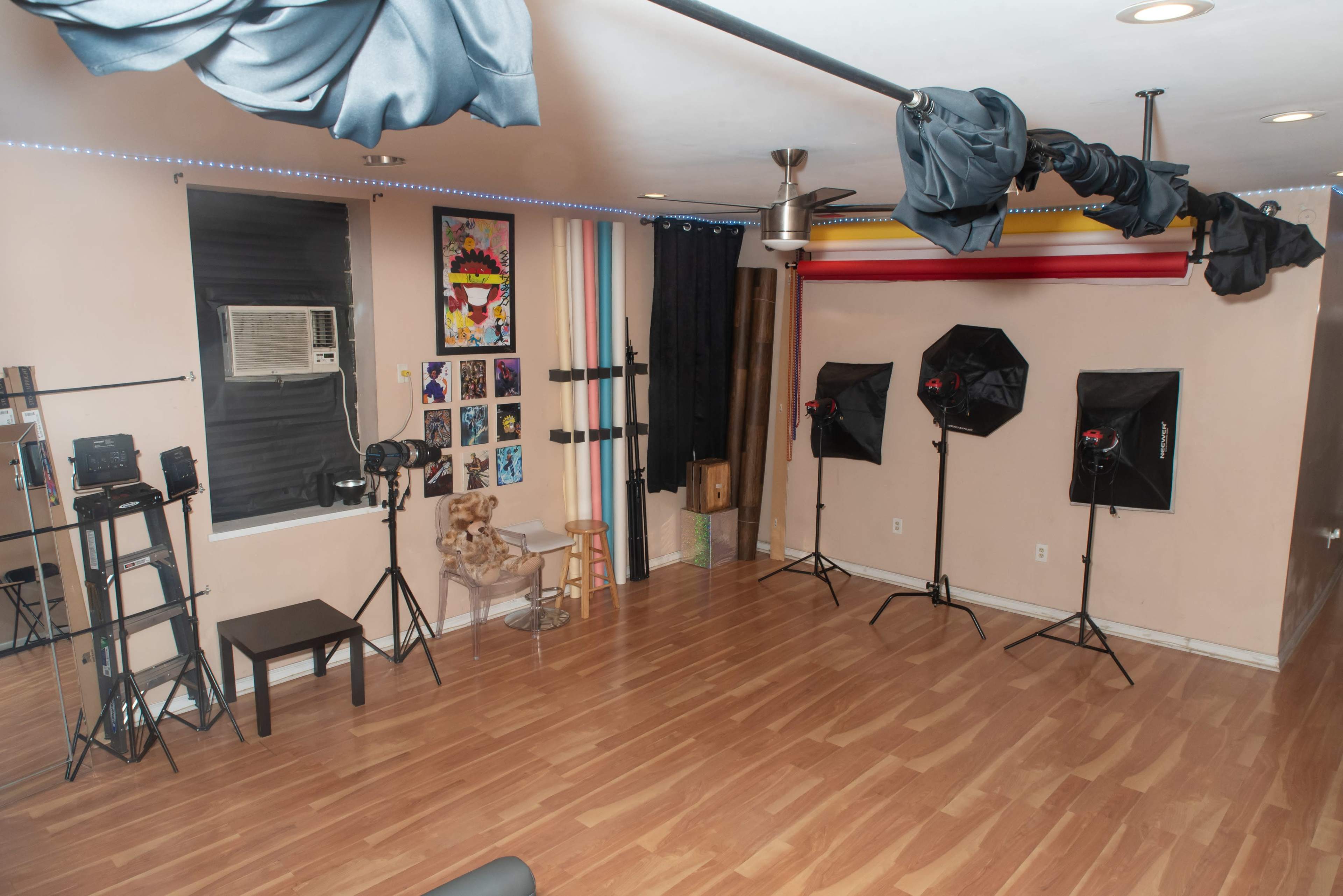 The image shows a photography studio equipped with various lights, a backdrop, and a seating area.